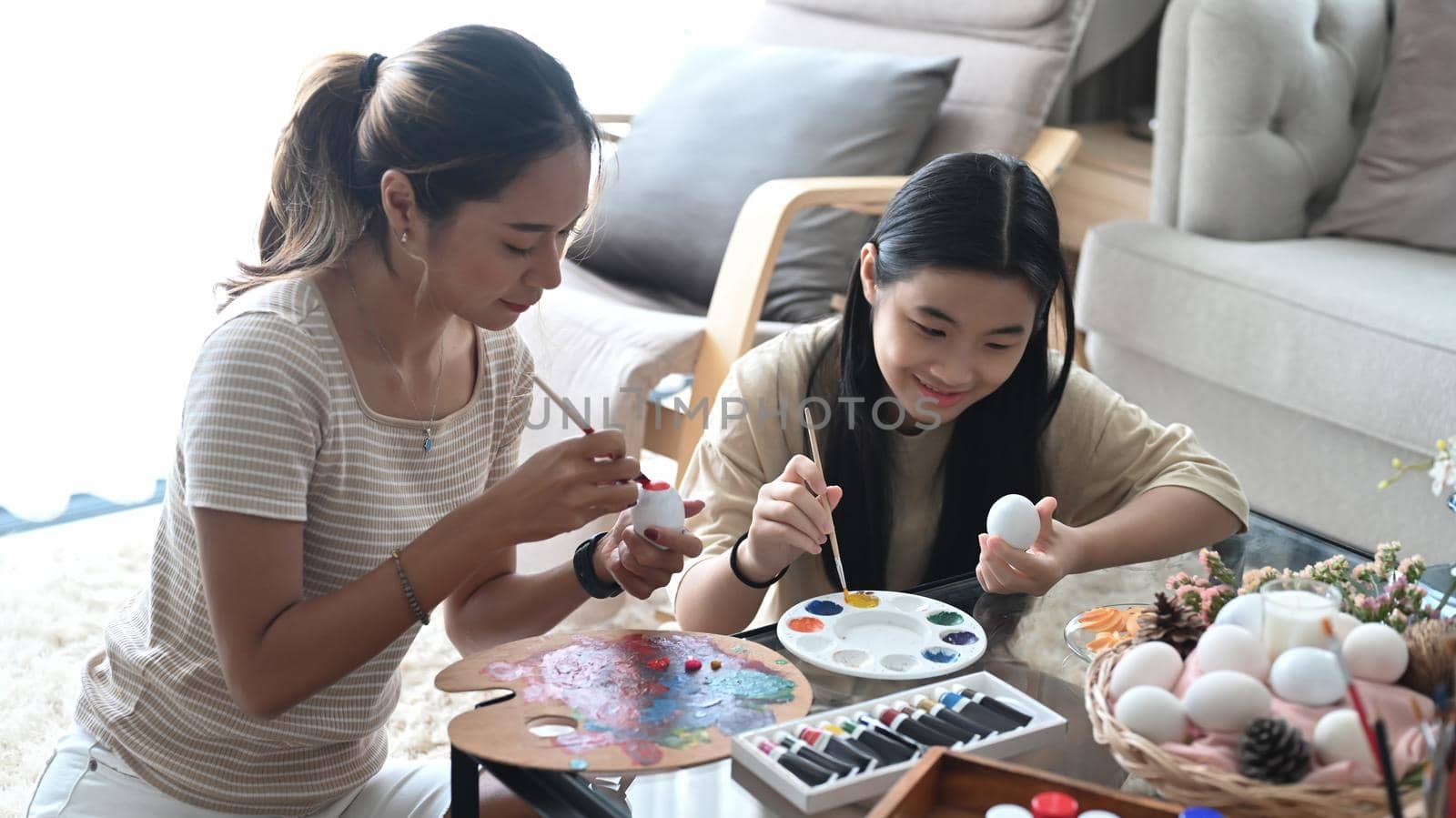 Mother and her daughter preparing for Easter celebration and spending leisure time together at home.