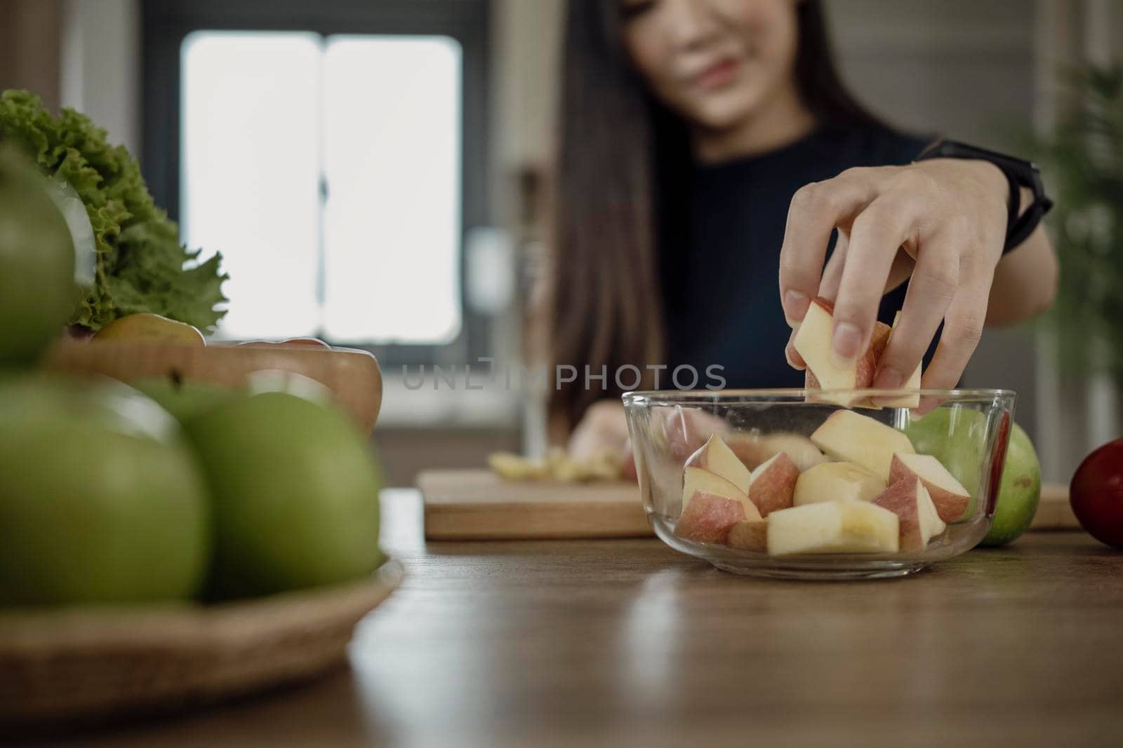 Young woman making fresh vegetarian salad in kitchen. Healthy and wellness concept.
