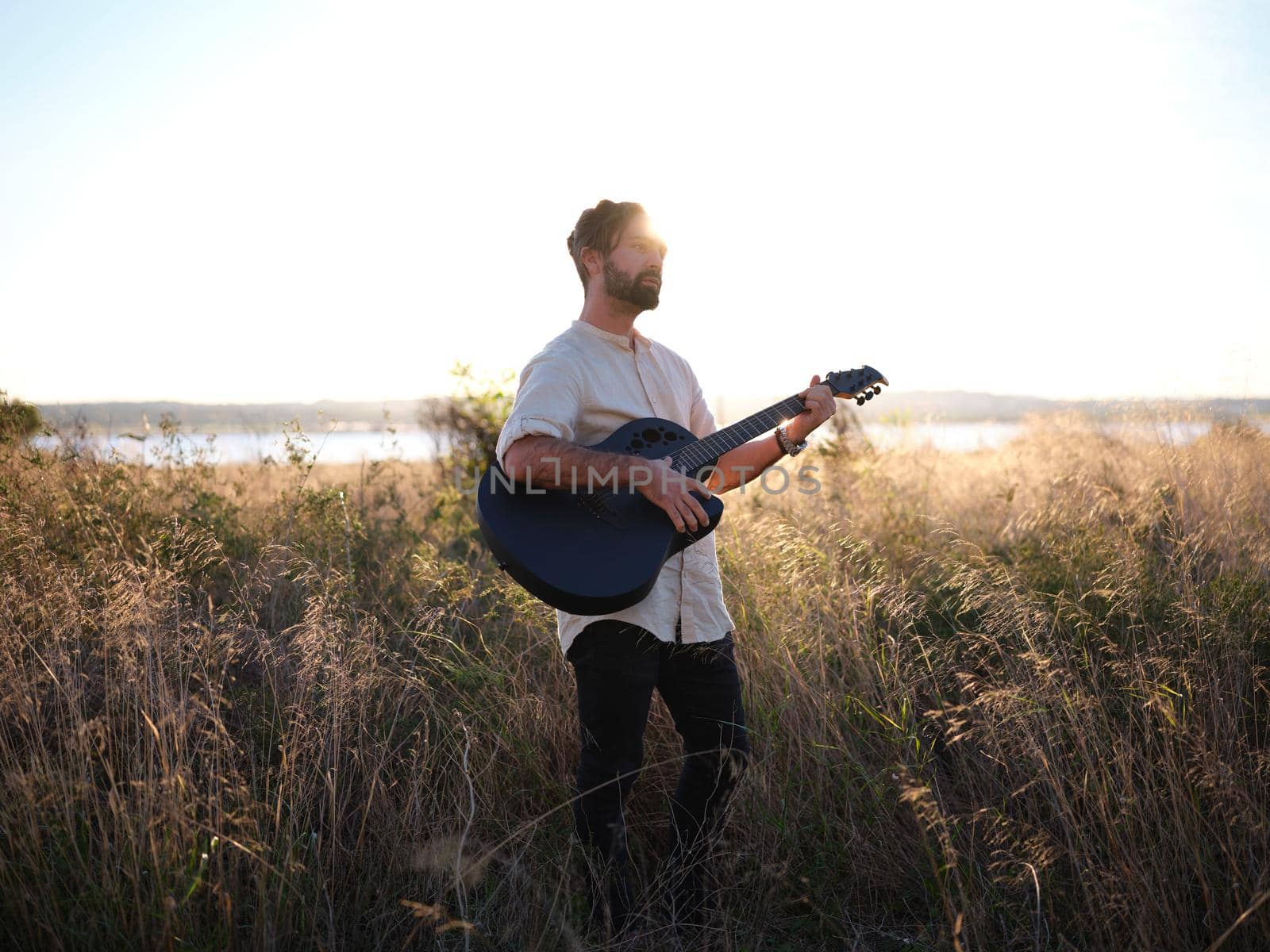 guitarist posing with his guitar in the countryside during sunset, horizontal portrait