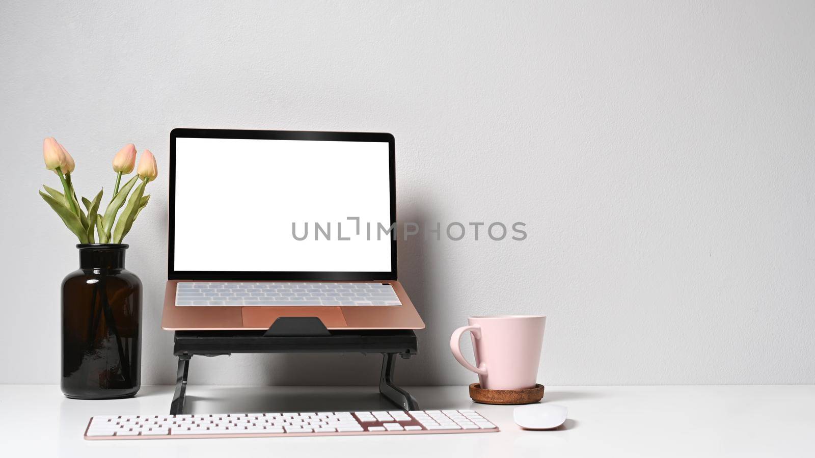 Mockup computer laptop, flower pot and coffee cup on white table.