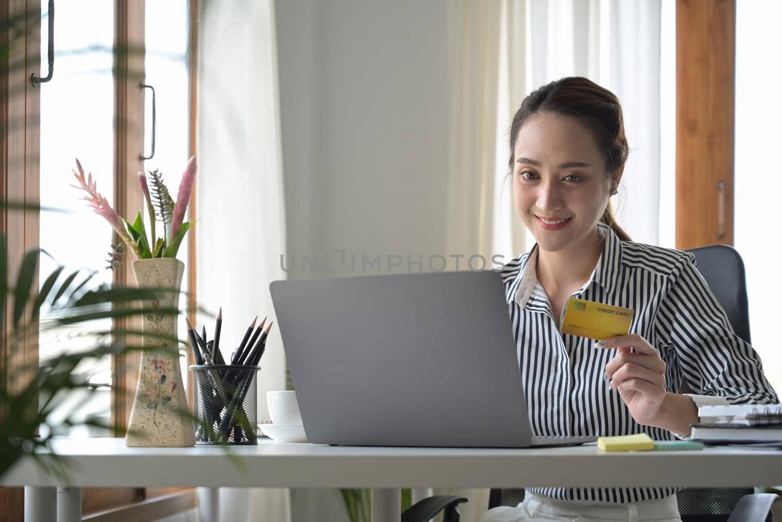 Charming woman holding credit card and shopping online on laptop computer. by prathanchorruangsak