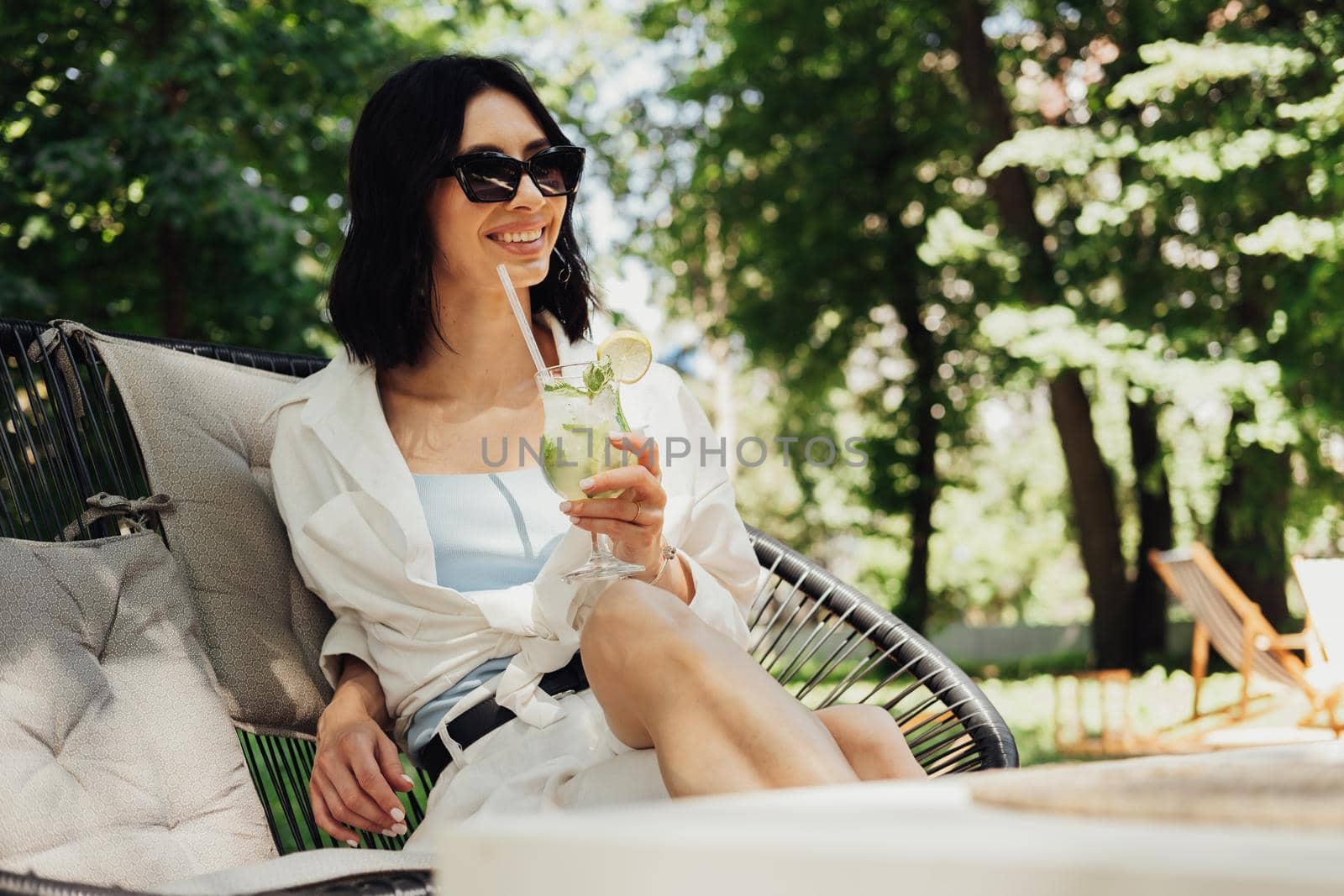 Young Brunette Woman Relaxing and Drinking Cocktail While Sitting on the Restaurant Terrace Outdoors in Summer Sunny Day
