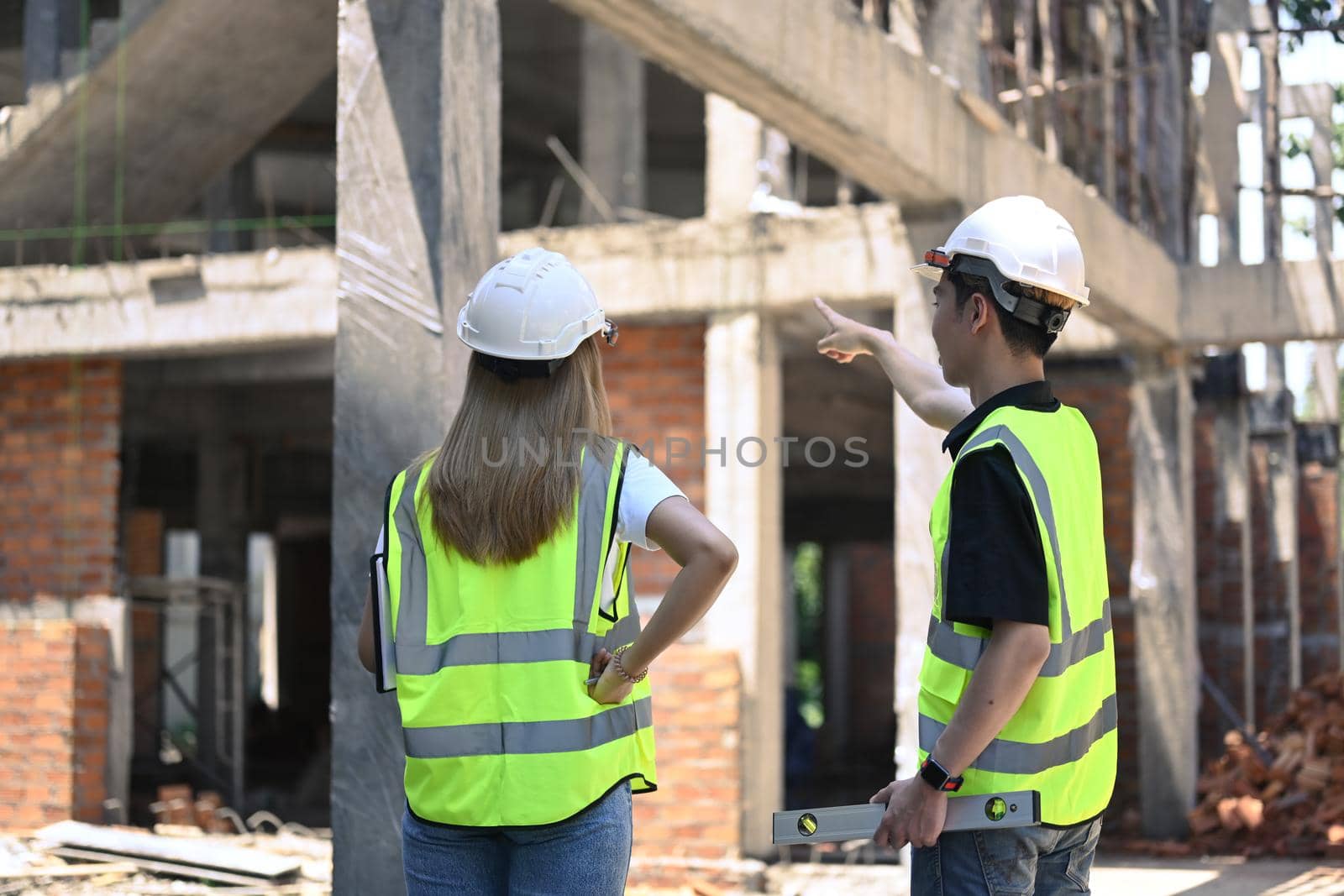 Back view of two engineer discussing new plan at construction site.