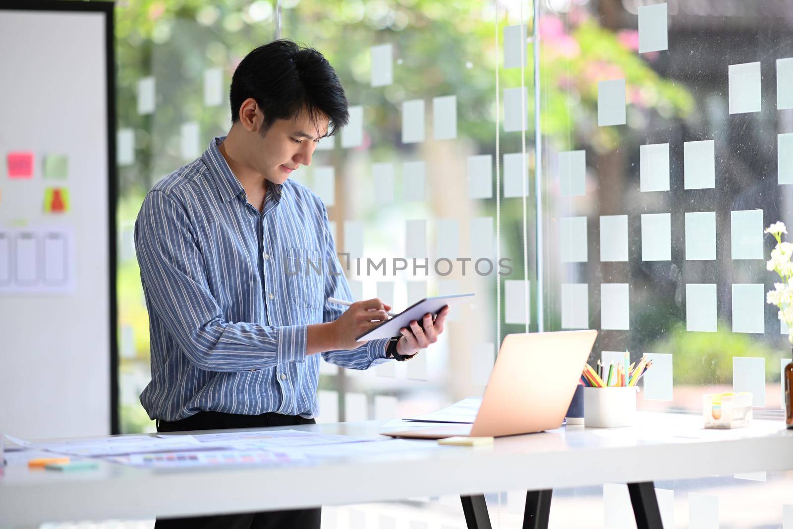 Asian male professionals web developer working on software development and using modern devices at creative office.