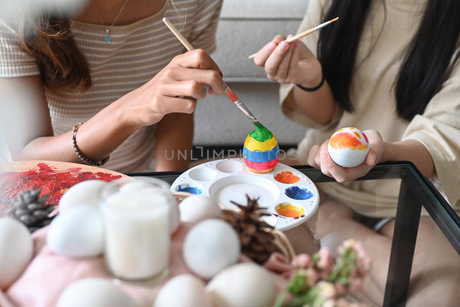 Mother helping her daughter painting easter eggs. Easter, holidays and people concept. by prathanchorruangsak