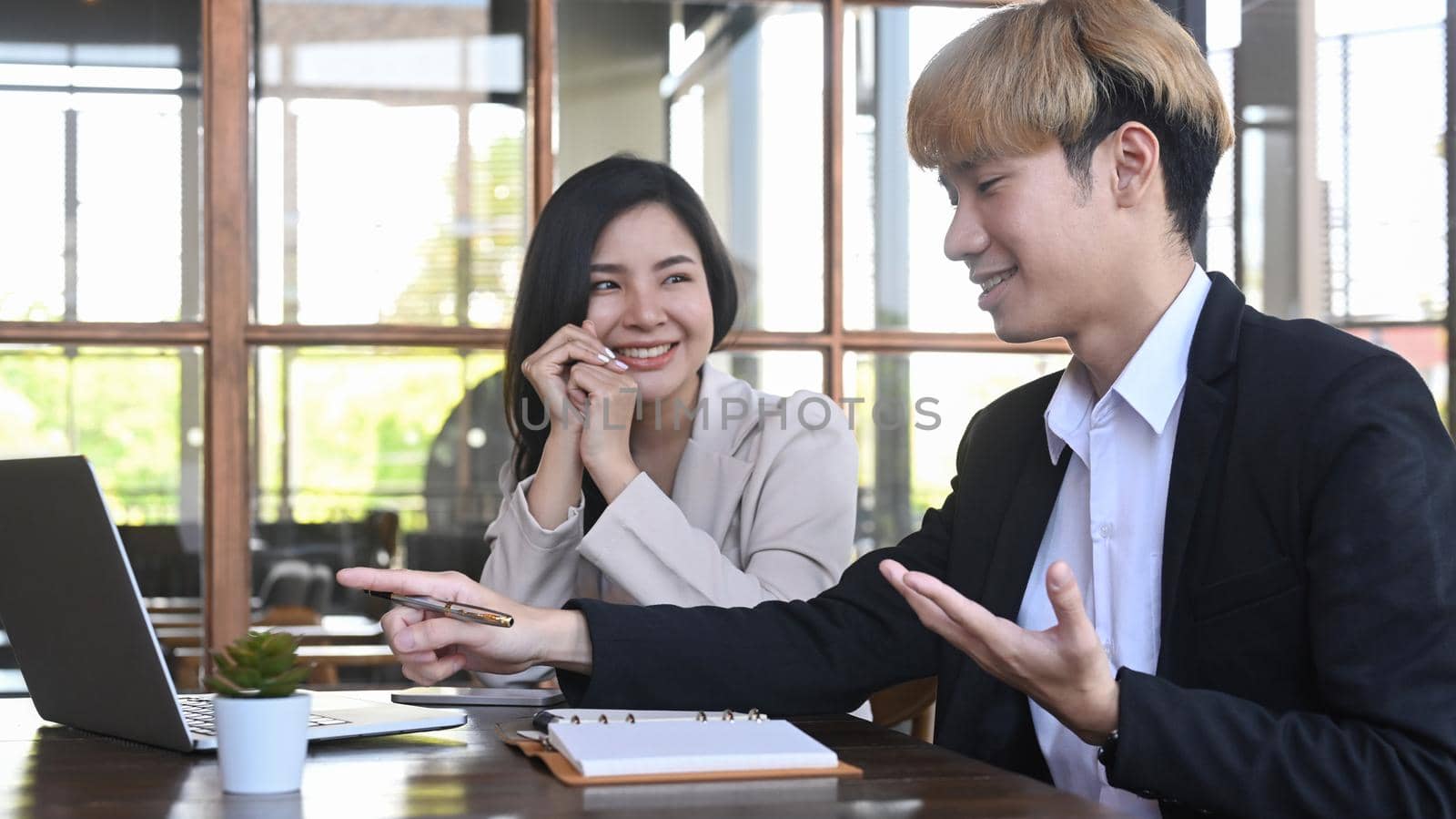 Male business team leader explaining online project to colleagues while sitting at co working space.