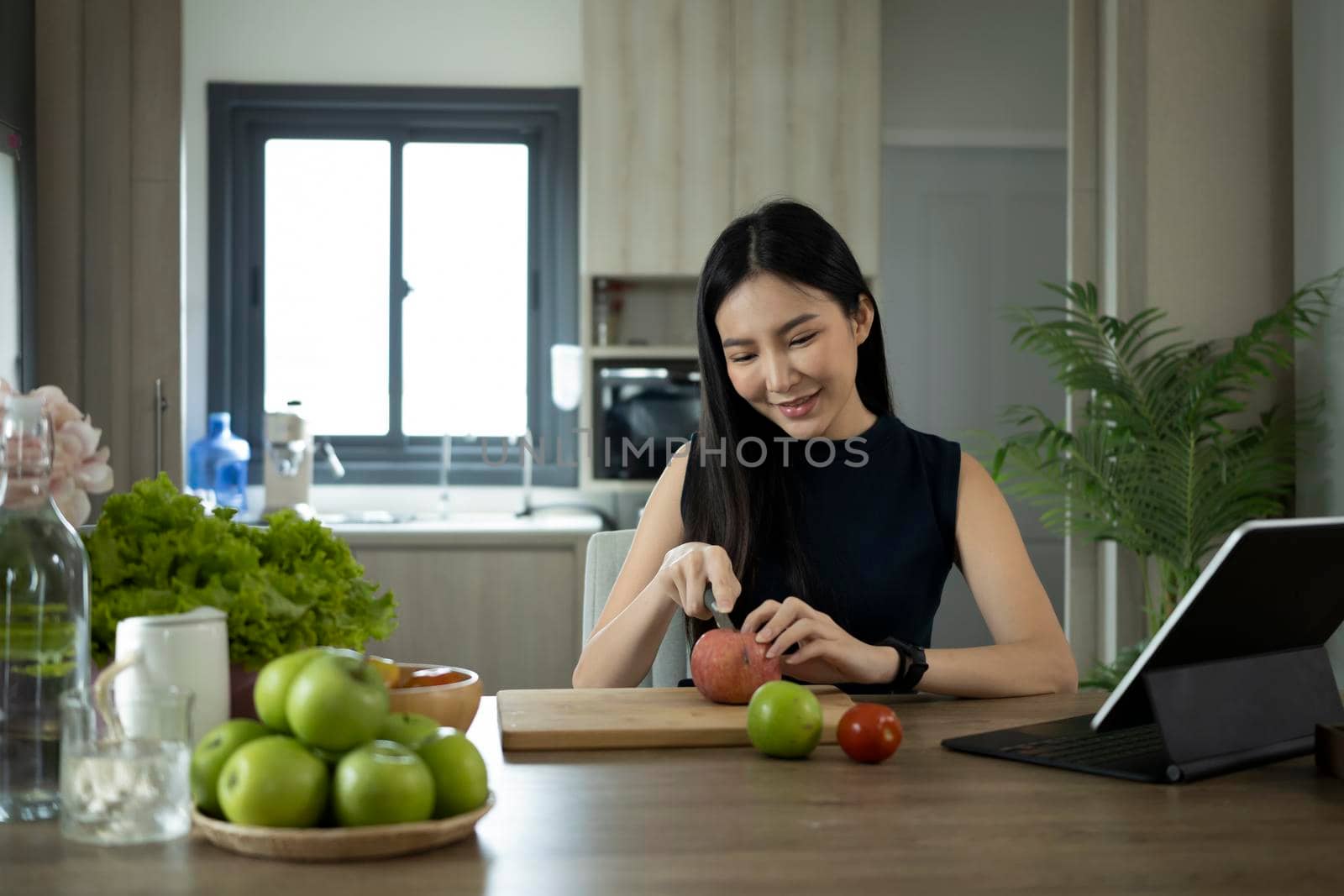 Happy millennial woman preparing ingredients for making healthy organic salad in kitchen. Diet and Healthy food concept. by prathanchorruangsak