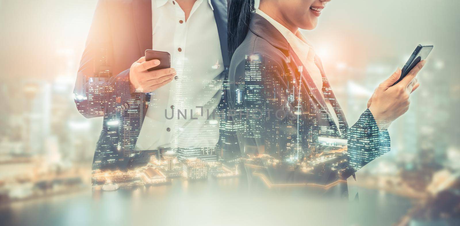 Young business people using mobile phone with modern city buildings background. Future telecommunication technology and internet of things ( IOT ) concept.