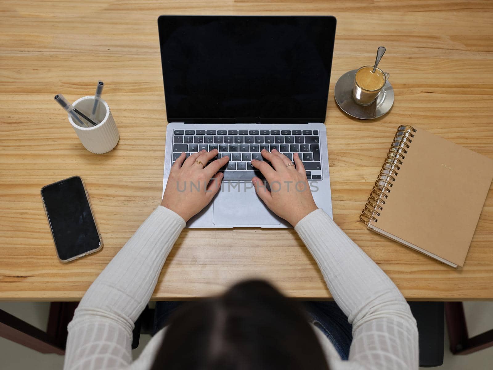 top view of the work area of an entrepreneurial woman with a laptop, notebook, phone and a coffee