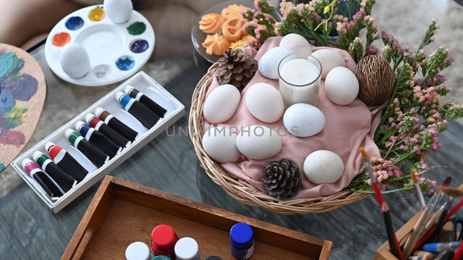Wicker basket with eggs and spring flowers on wooden table. Easter celebration concept. by prathanchorruangsak