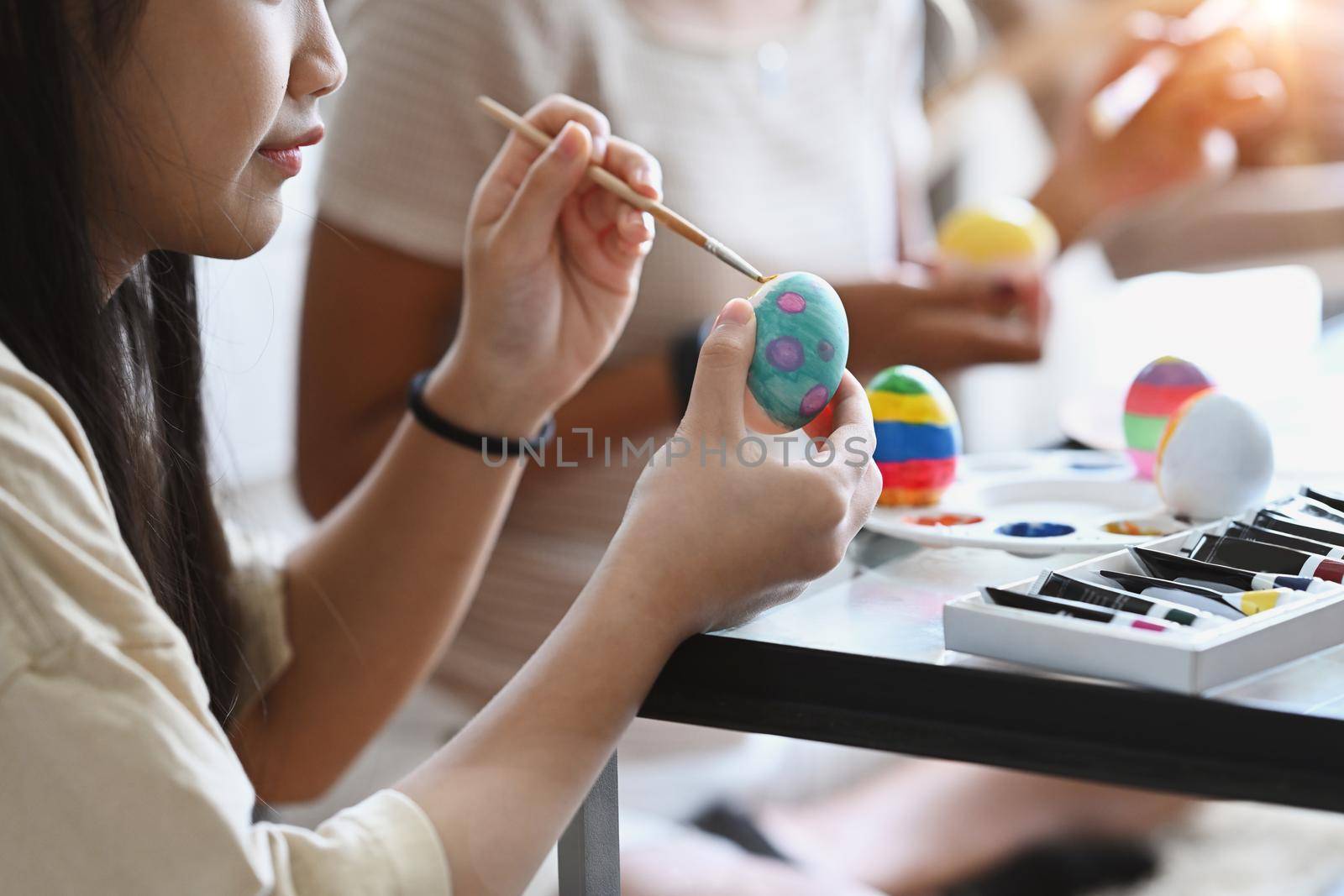 Little girl and mother coloring eggs for Easter, preparing for Easter day. Ester concept. by prathanchorruangsak