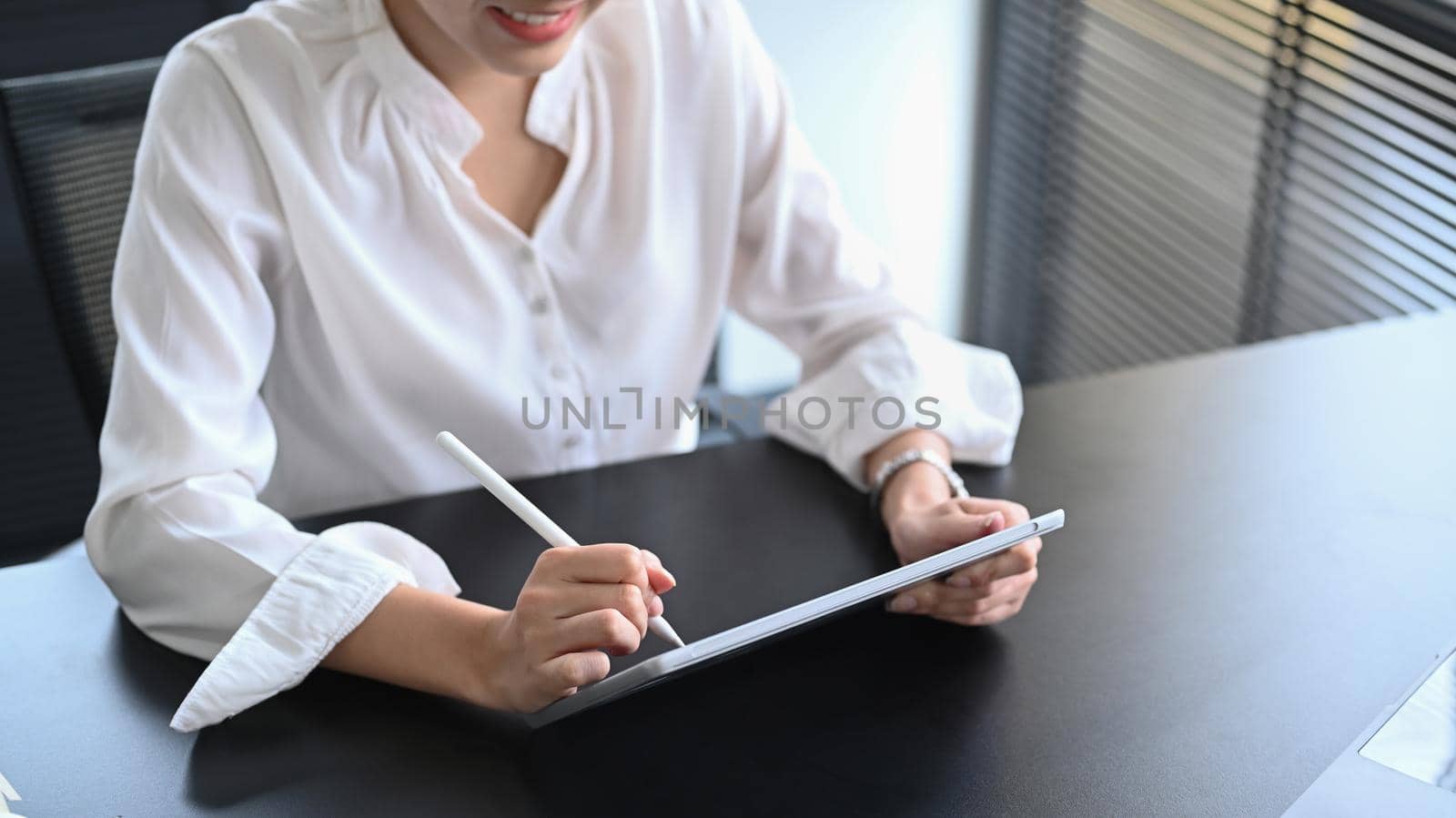 Professional businesswoman using digital tablet and preparing annual financial report at office desk.