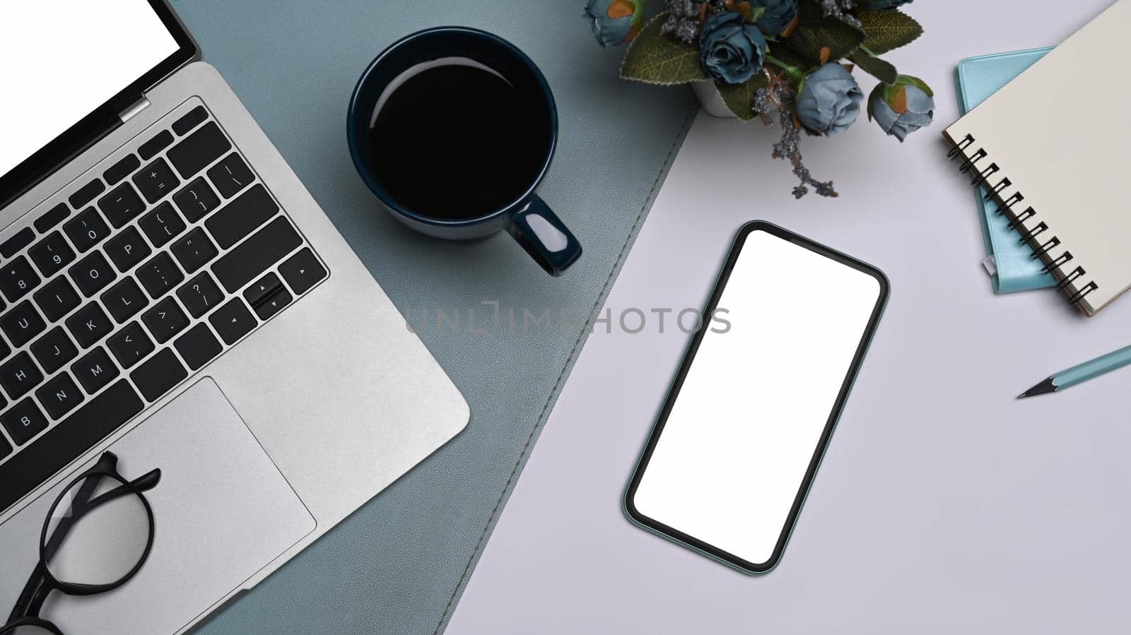 Mobile phone with blank screen, laptop computer, coffee cup and notebook on white table. Flay lay.