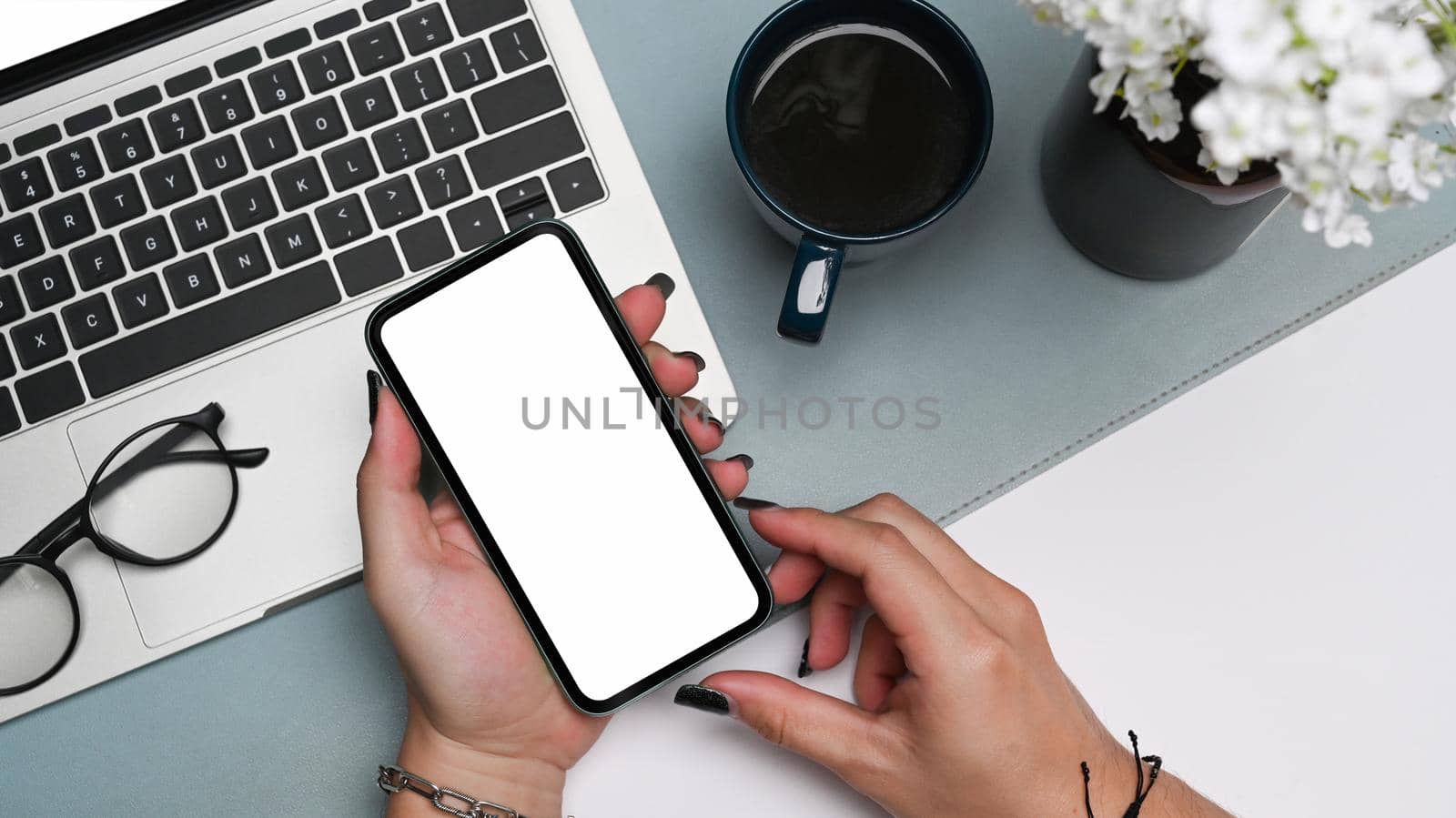 Woman hands holding mobile phone with white screen at her office desk. by prathanchorruangsak