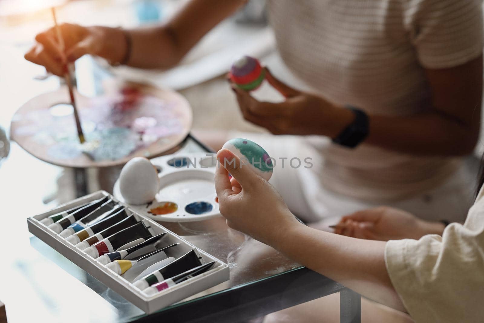 Mother and daughter painting Easter eggs, preparing for Easter day.