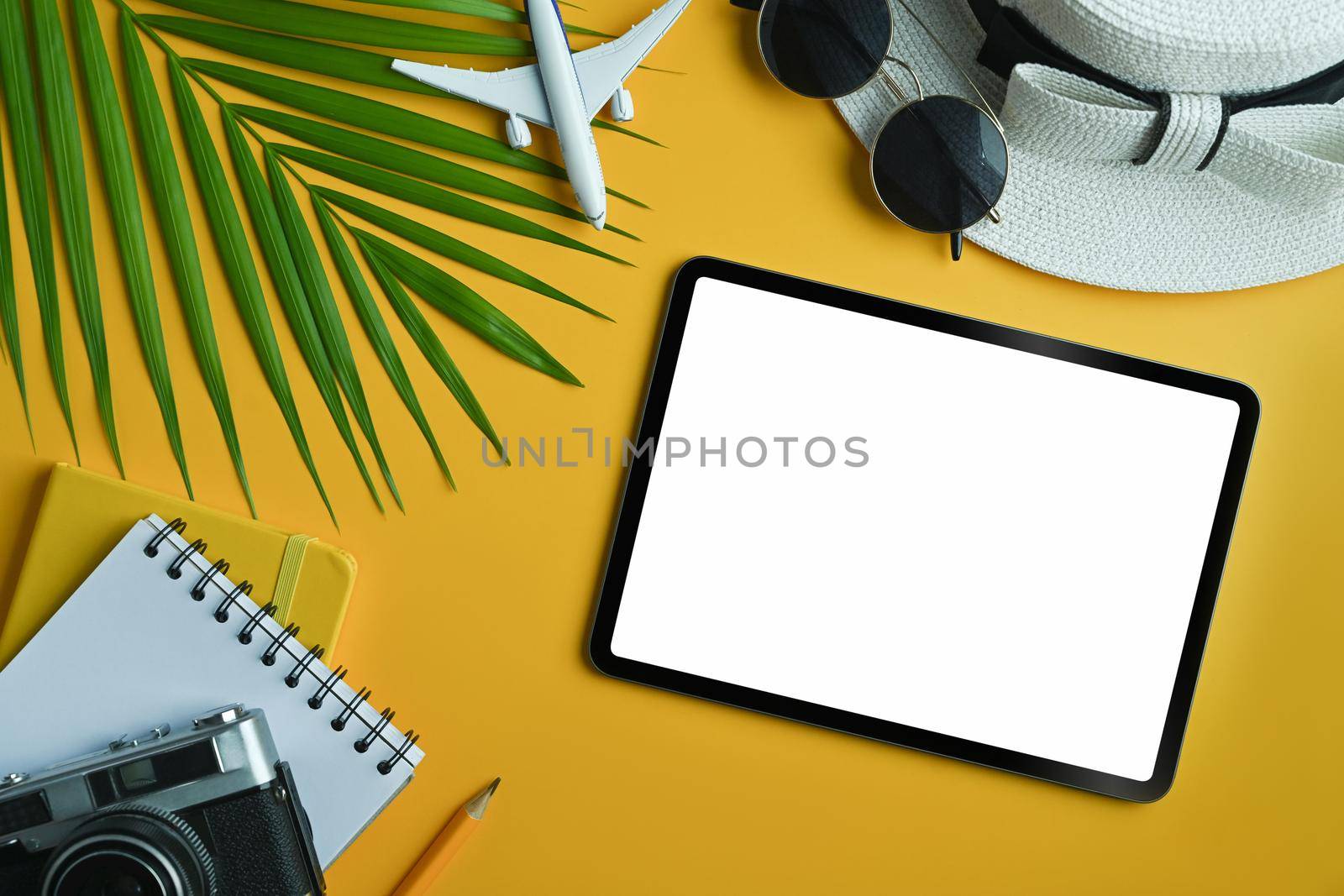 Flat lay digital tablet with blank screen and traveler accessories on yellow background. Travel, summer and holiday concept. by prathanchorruangsak