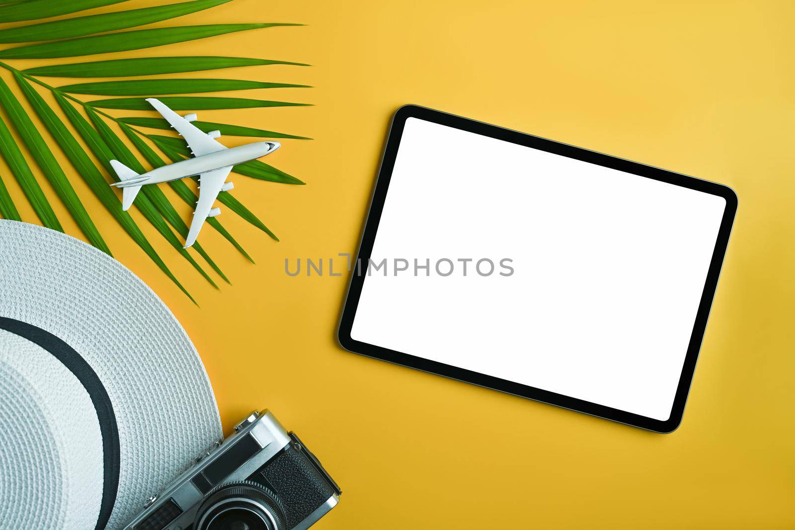 Digital tablet and traveler accessories on yellow background. Travel, summer and holiday concept. by prathanchorruangsak