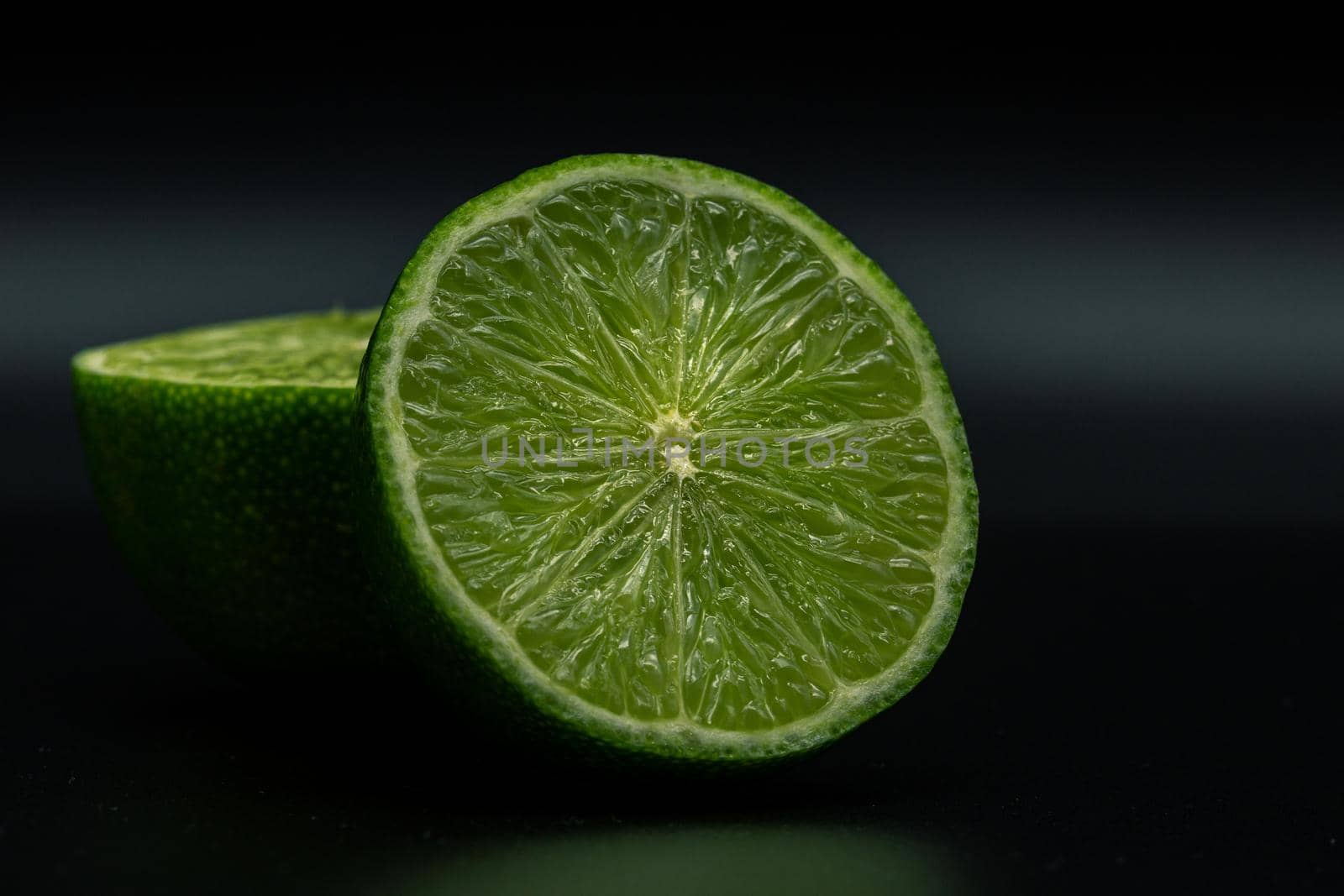 Green lime citruss fruit cutting half macro fiber inside, black background