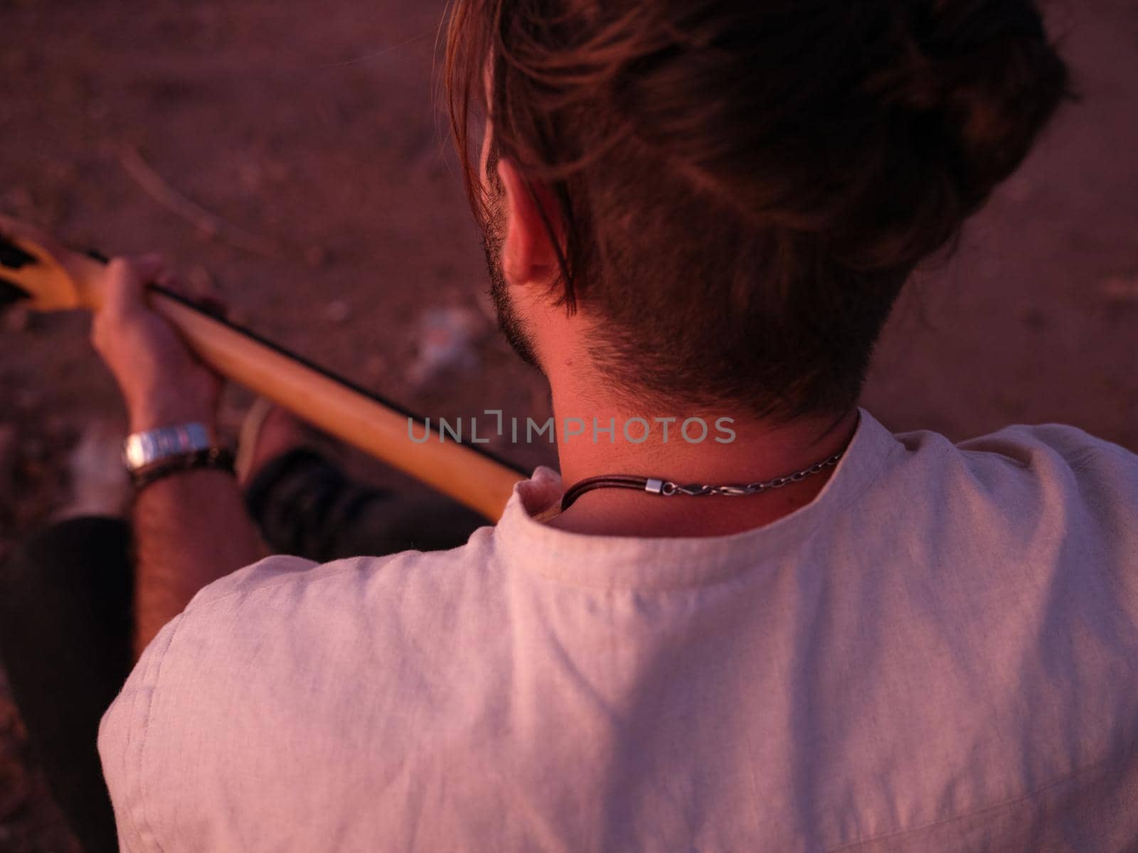 cut out view from behind of a seated man playing the guitar, horizontal close up