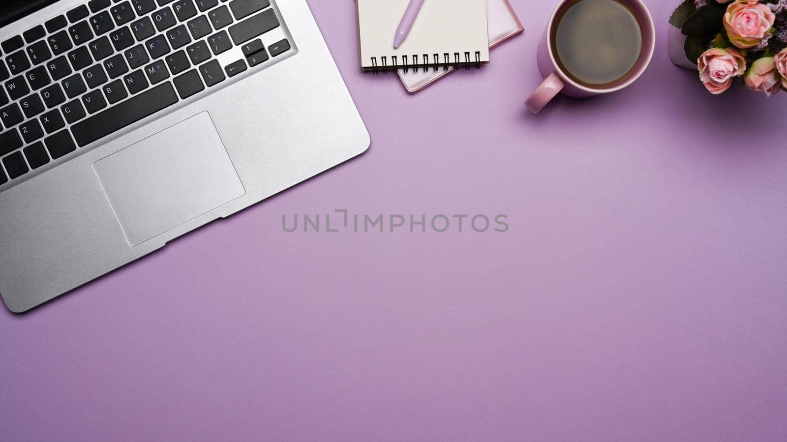 Laptop computer, notepad, and coffee cup on purple background. Flat lay, Top view.