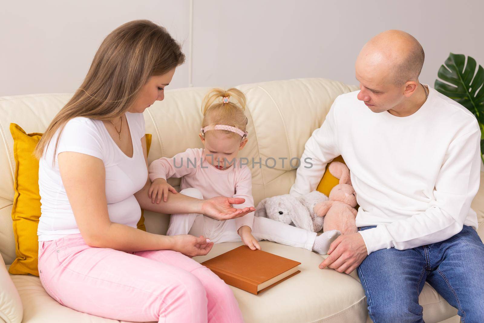 Cochlear implant on the child girl head and playing with mother and father. Hearing aid and deafness and innovative health technology and diversity concept by Satura86