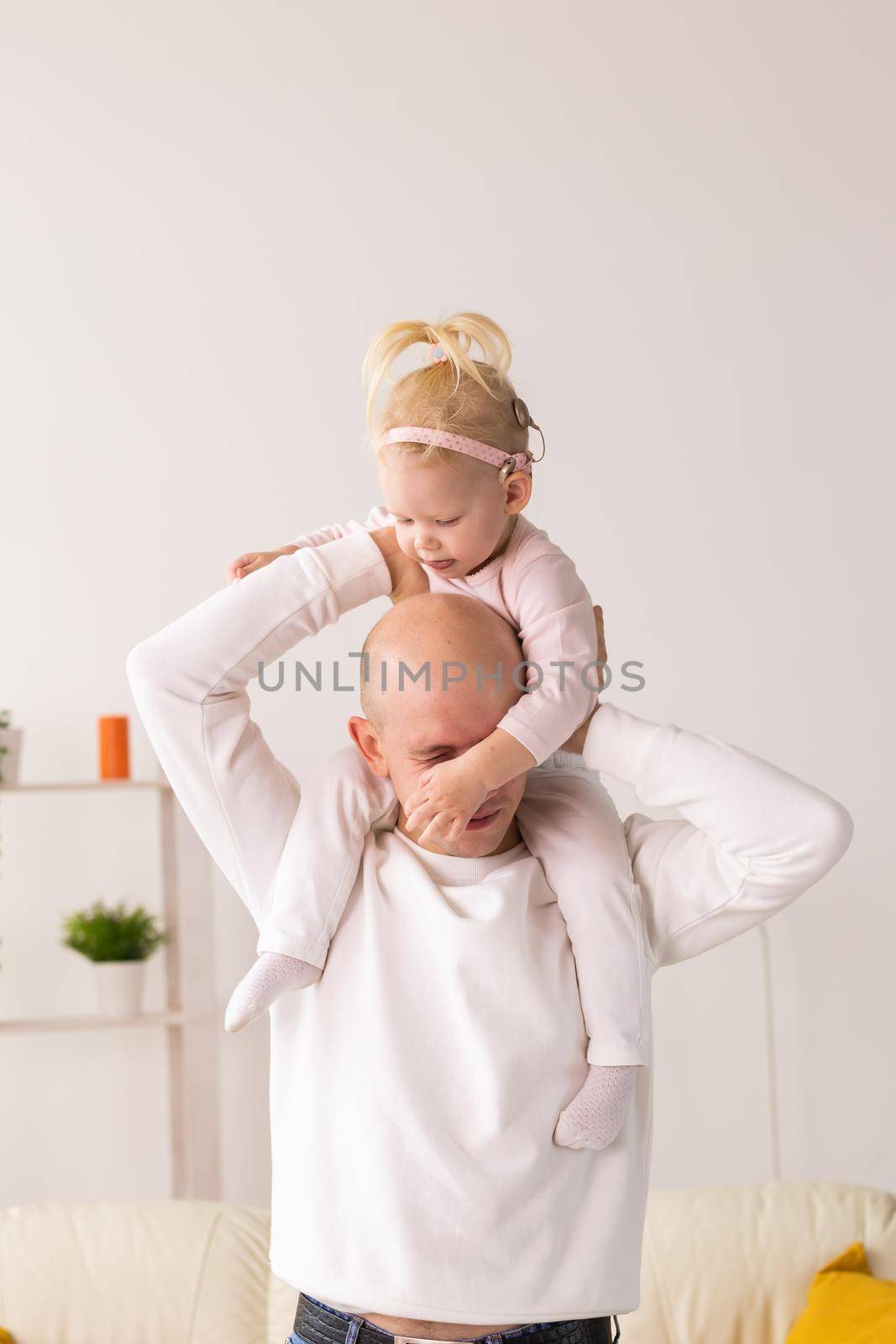 Happy child girl with cochlear implant having fun with her father - hearing aid for deaf and innovative health technology and diversity concept by Satura86