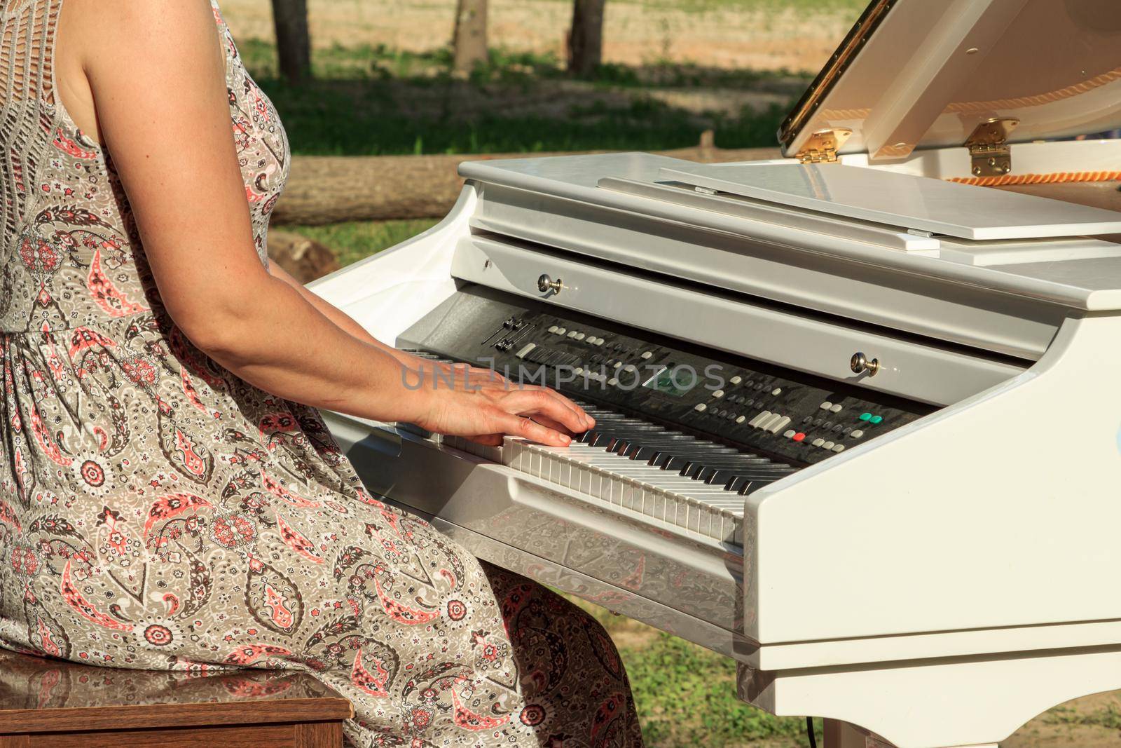 Lady hands playing white electric piano outdoors, keyboard with dust