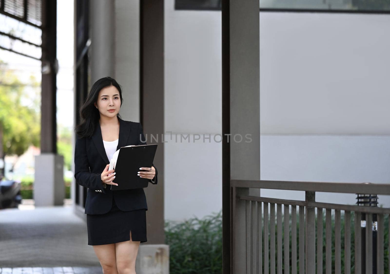 Confident female manager in suit walking at modern office district.