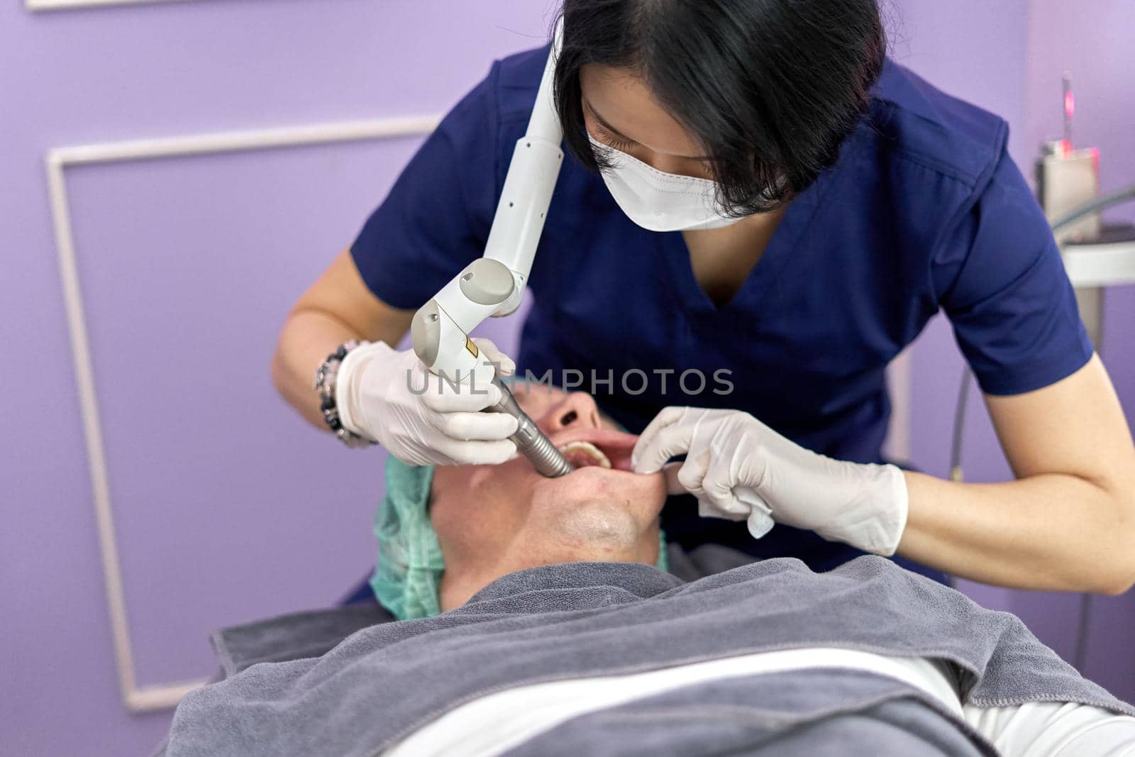 Doctor applying a facial rejuvenation treatment using laser to a patient lying on a stretcher