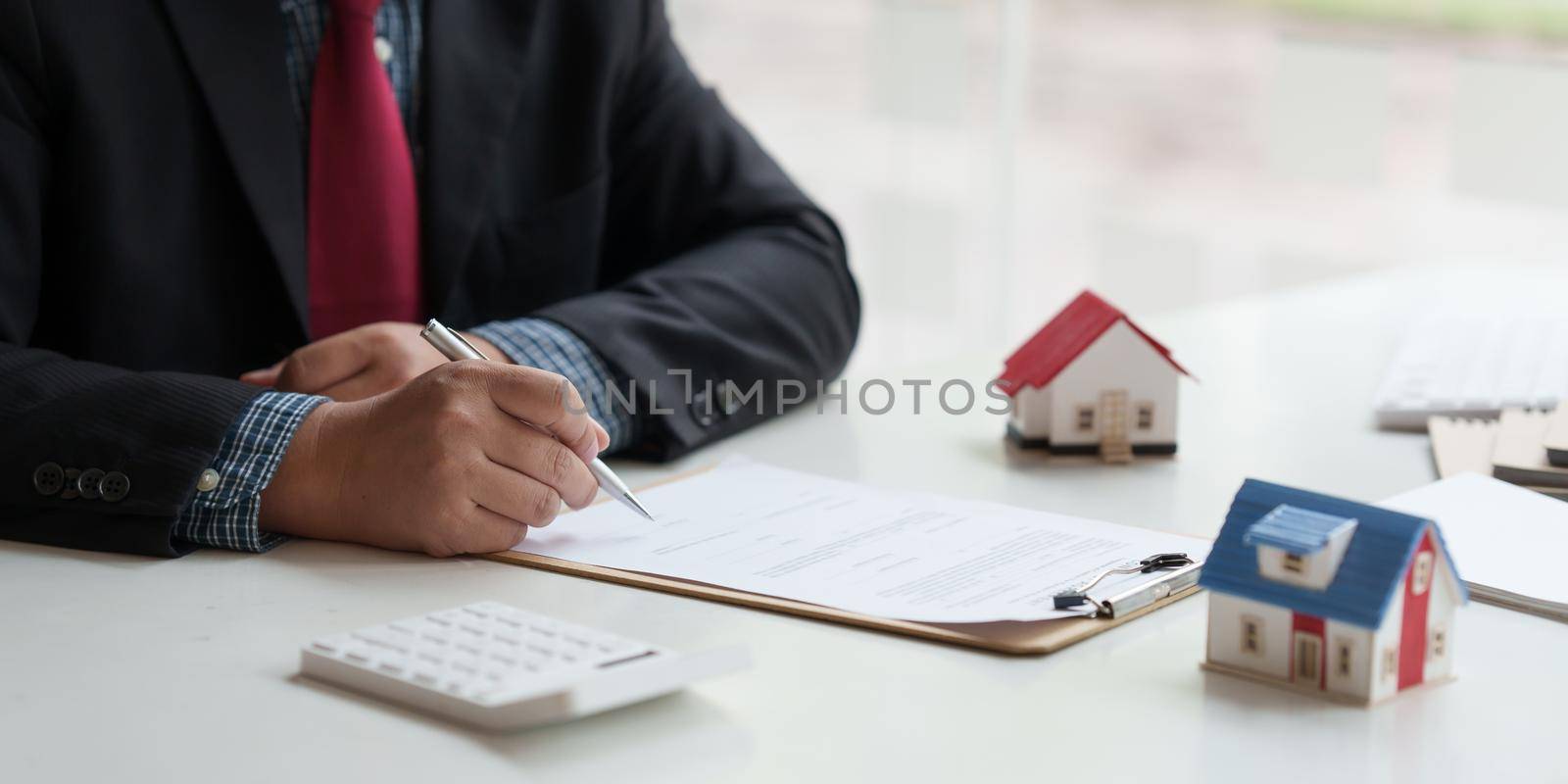 Close up of Businessman pointing and signing agreement for buying house. Bank manager concept