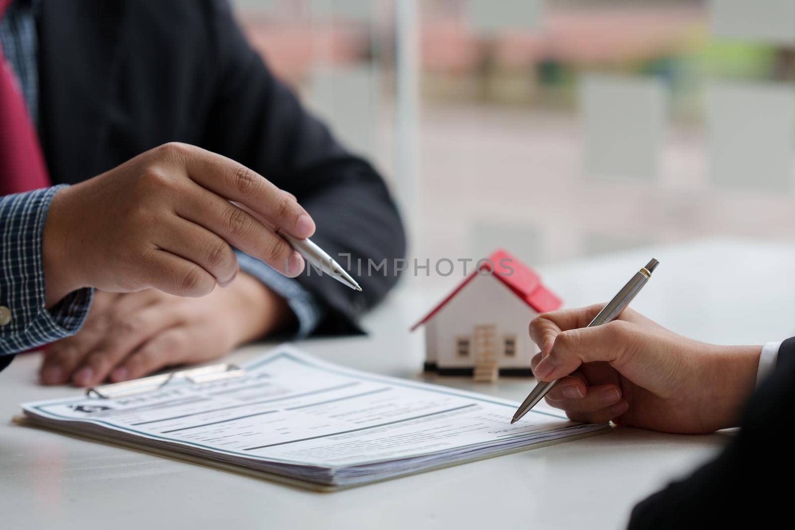 Close up of Business man pointing and signing agreement for buying house. Bank manager concept