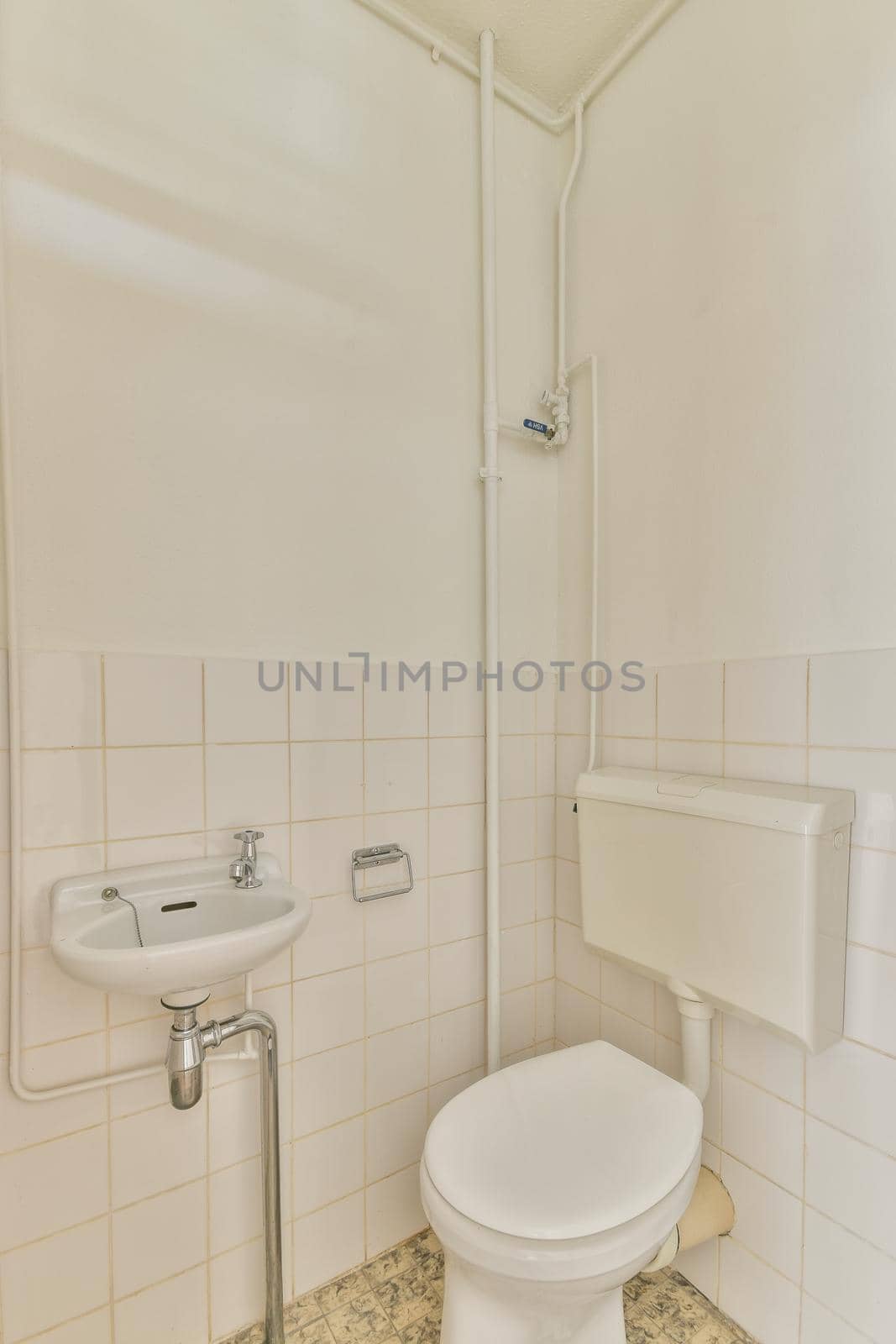 Modern flush toilet and ceramic sink installed on white tiled walls and towel in small restroom at home