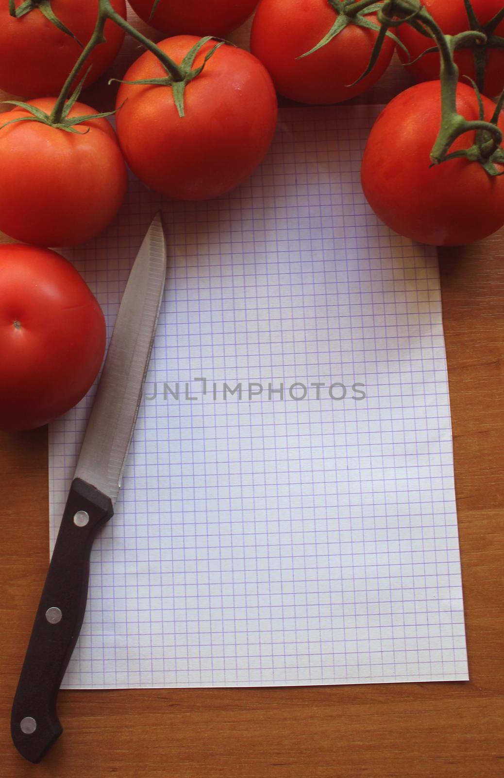 tomatoes on a wooden background with sheet of paper and knife by JackyBrown