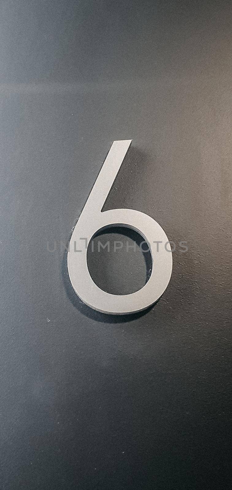 vertical photo of metallic number six on gray wall