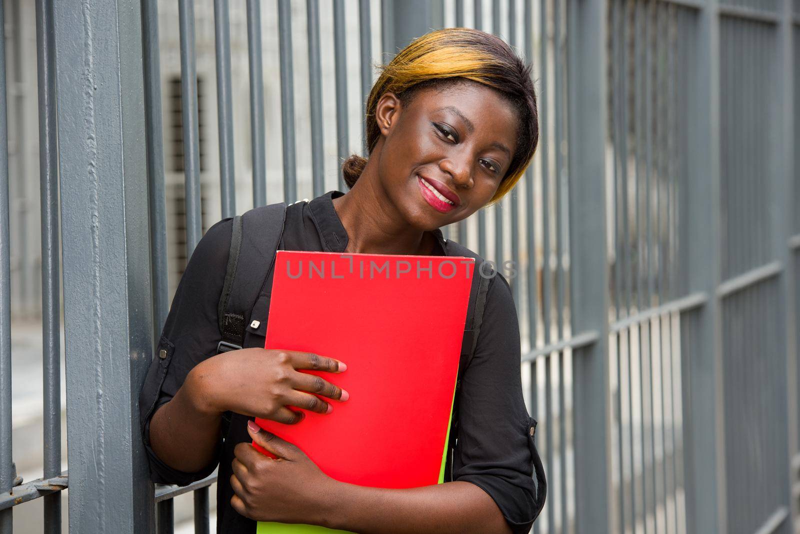 student standing near grid with documents looking at something smiling.