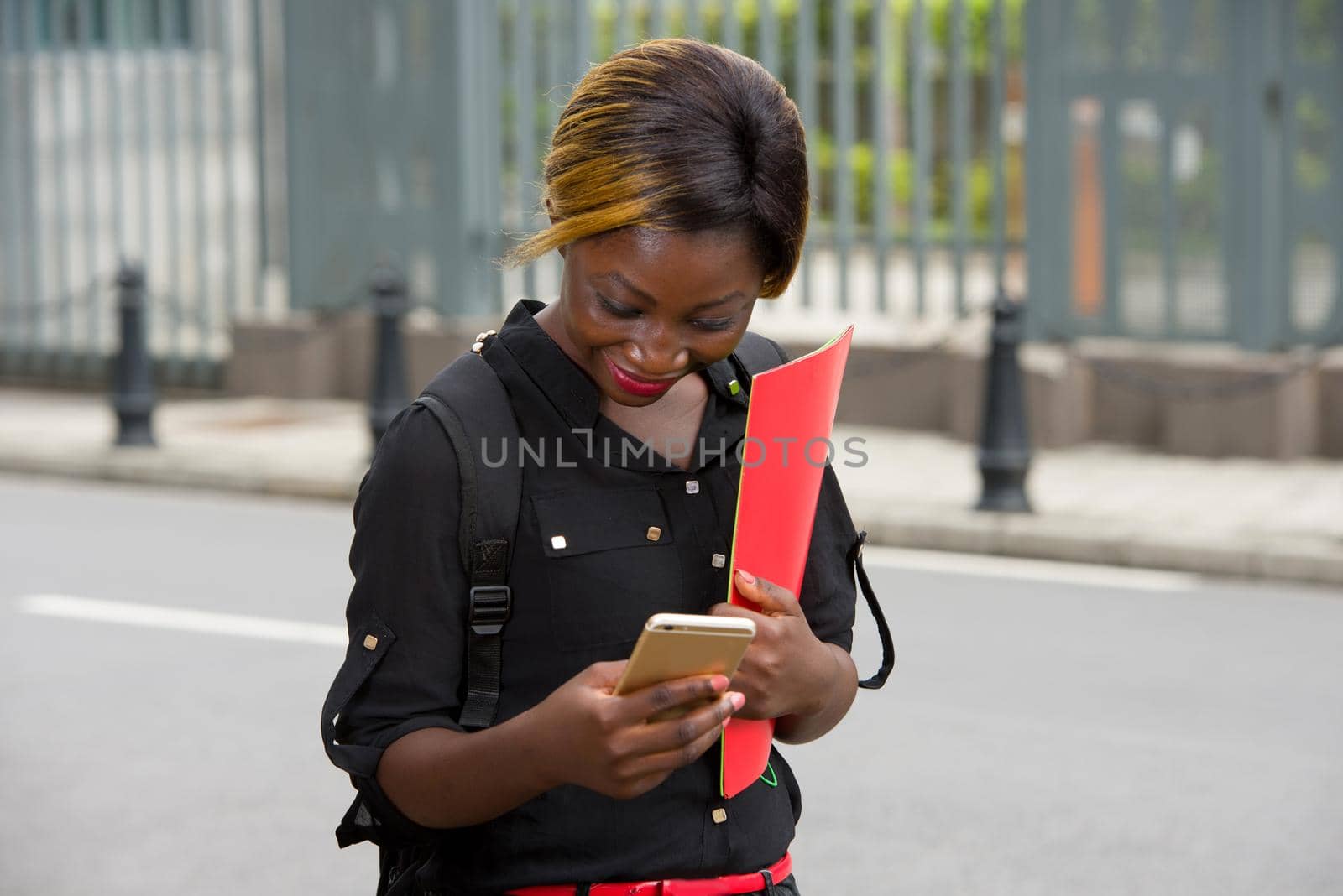 young student standing backpack going to look at mobile phone while smiling.