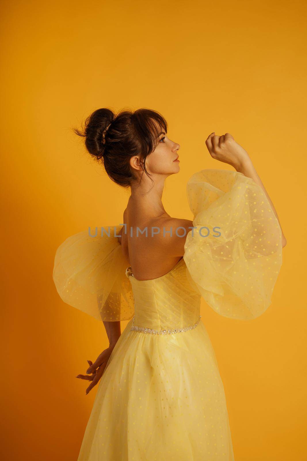 Profile portrait of a beautiful middle-aged woman in a yellow dress, her hair pulled up against a yellow background by Matiunina