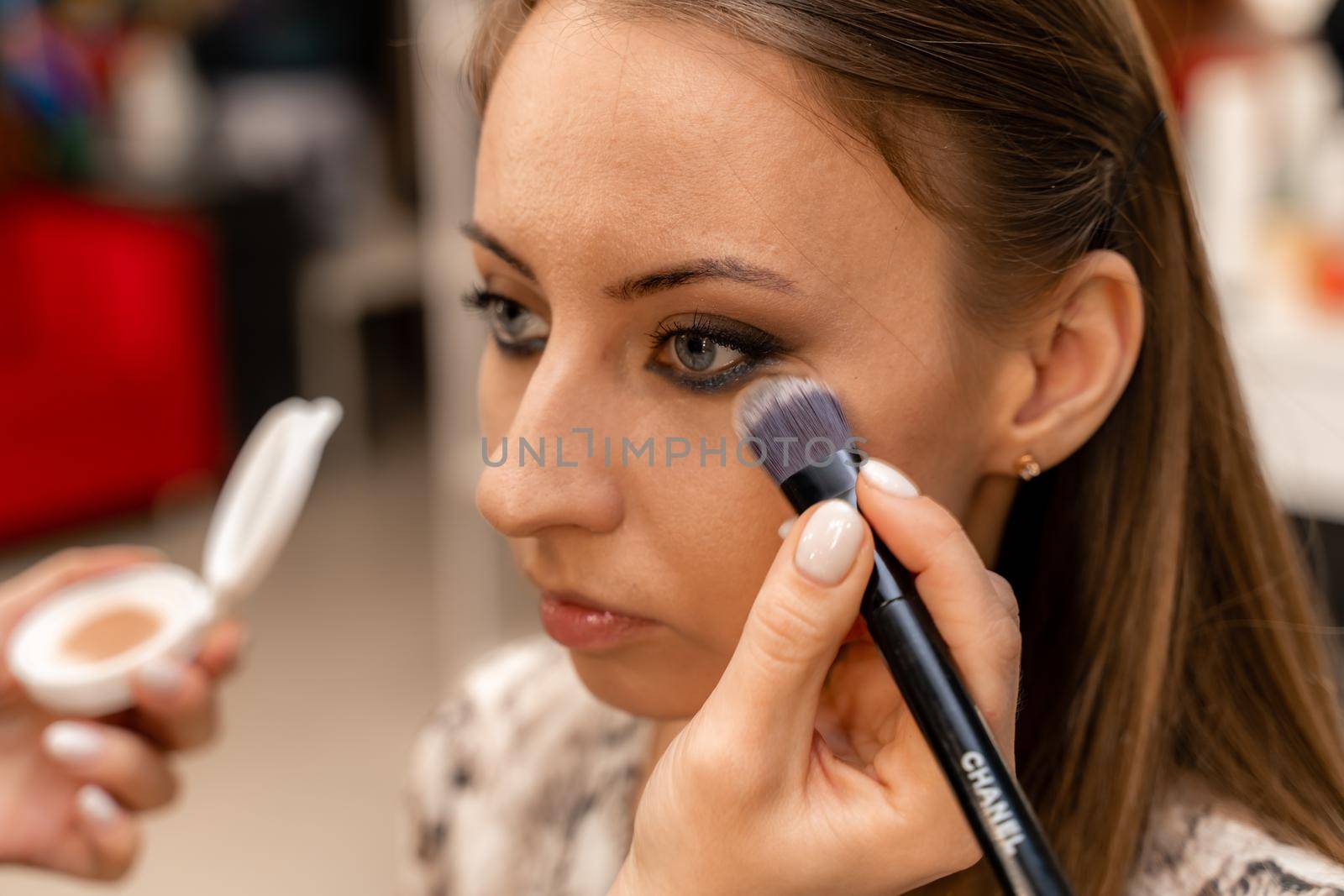 Make-up artist working with brush on model eyes Close up of applying make up on young girl,semi profile, professional make up in beauty studio by Matiunina