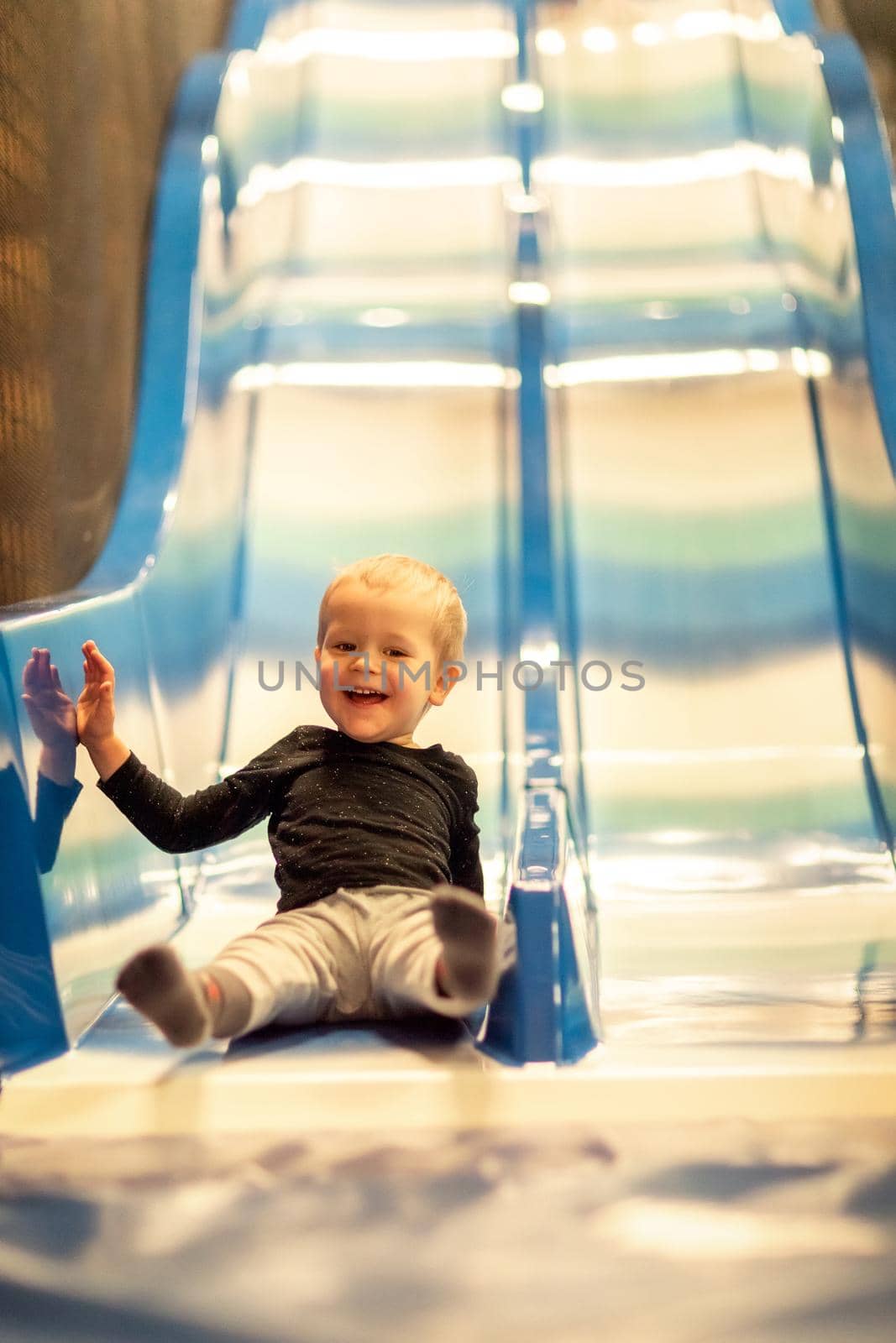 Kid riding from childrens slides in game center by Lincikas