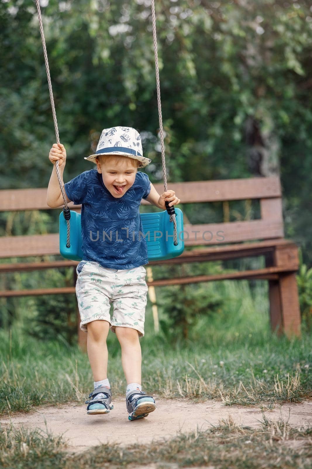 Adorable little boy playing in the garden with her swing. by Lincikas