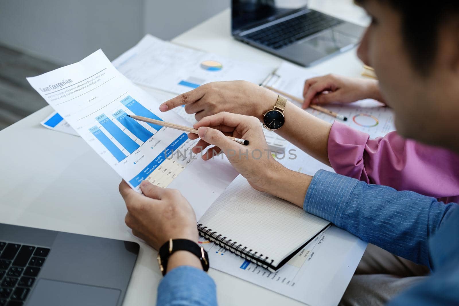 negotiation, analysis, discussion,asian male economist pointing out a document explaining the investment finance program to the company owner to plan marketing and hedging business risks. by Manastrong