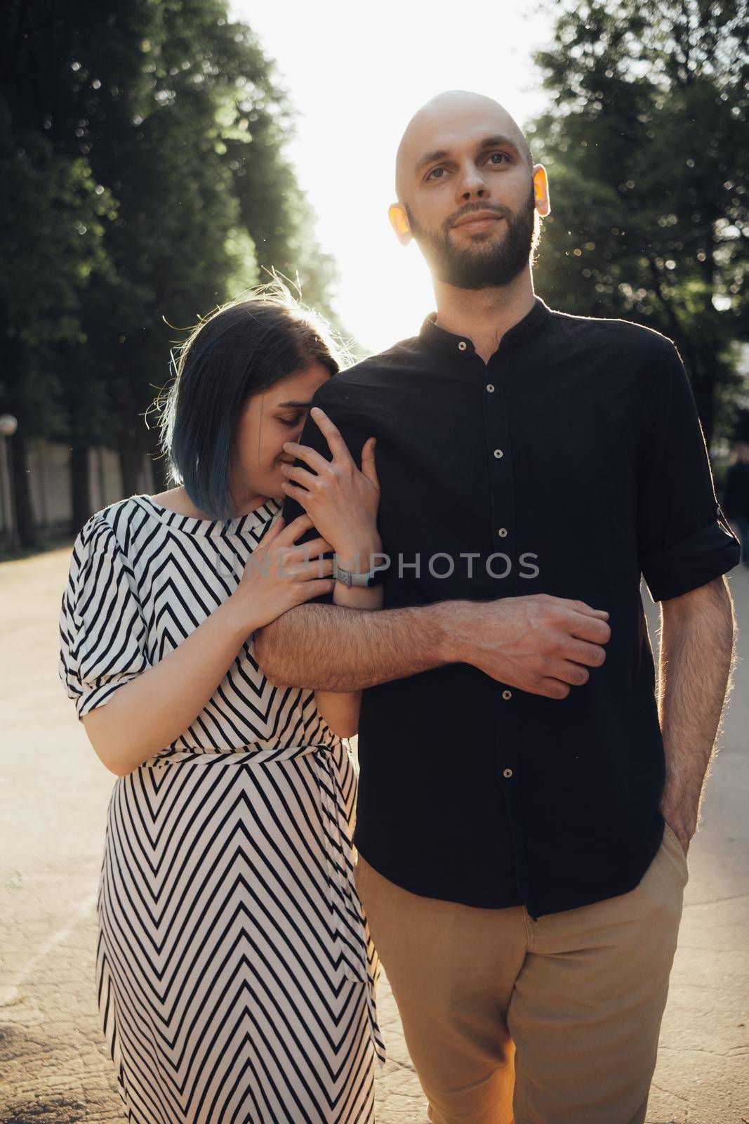 lovers take a walk in the park in the summer. the girl firmly holds the guy's hand by Symonenko