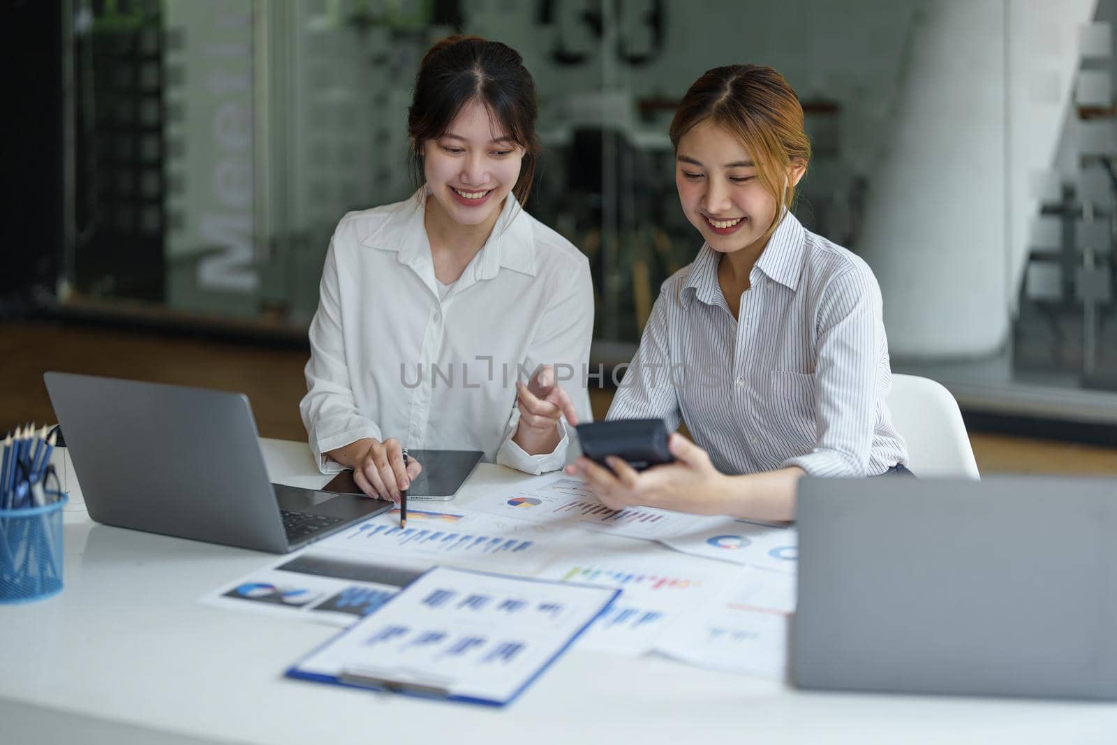 financial, Planning, Marketing and Accounting, portrait of Asian woman Economist using calculator to calculate investment documents with partners on profit taking to compete with other companies by Manastrong