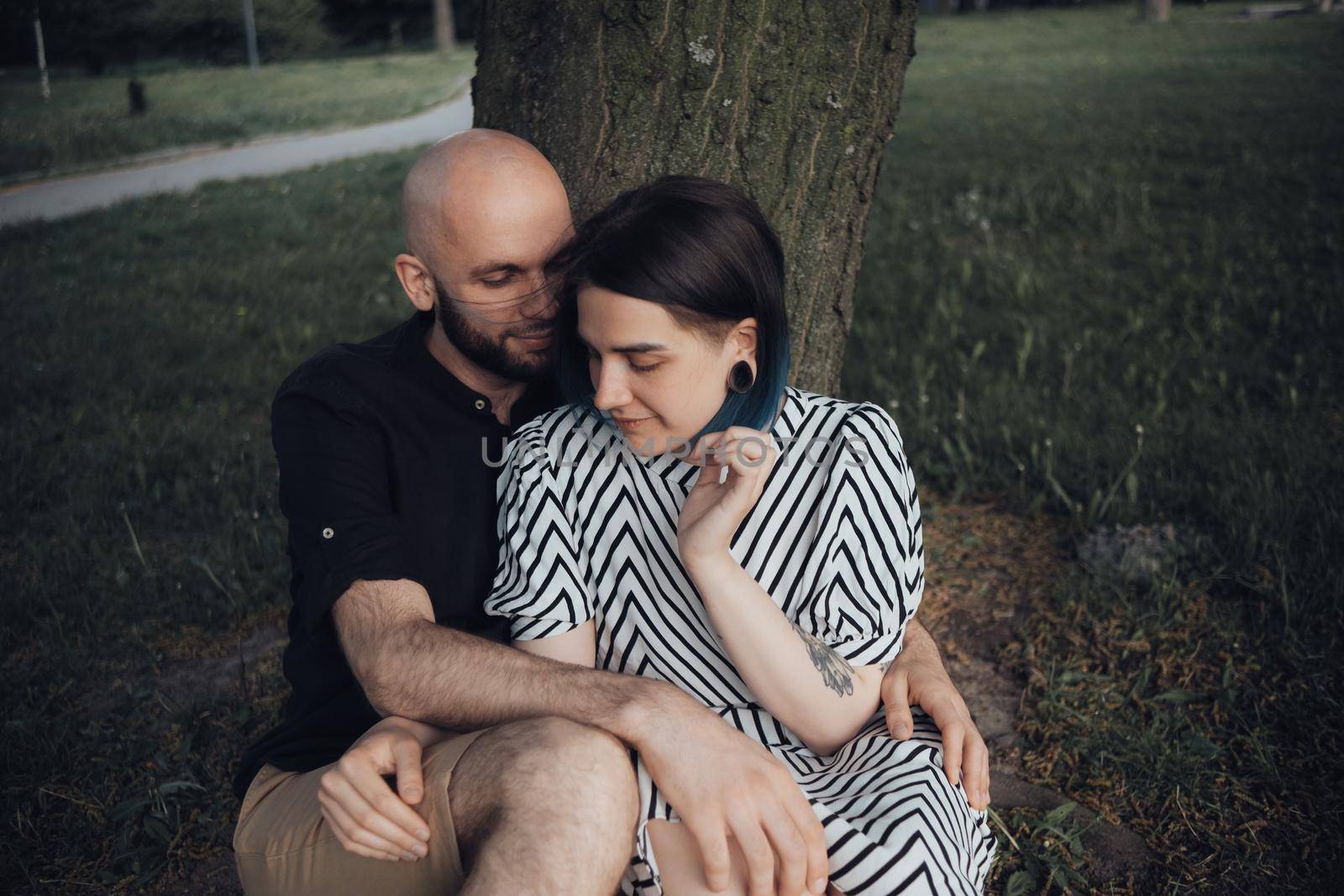lovers sit in the park under a tree, talk and hug by Symonenko