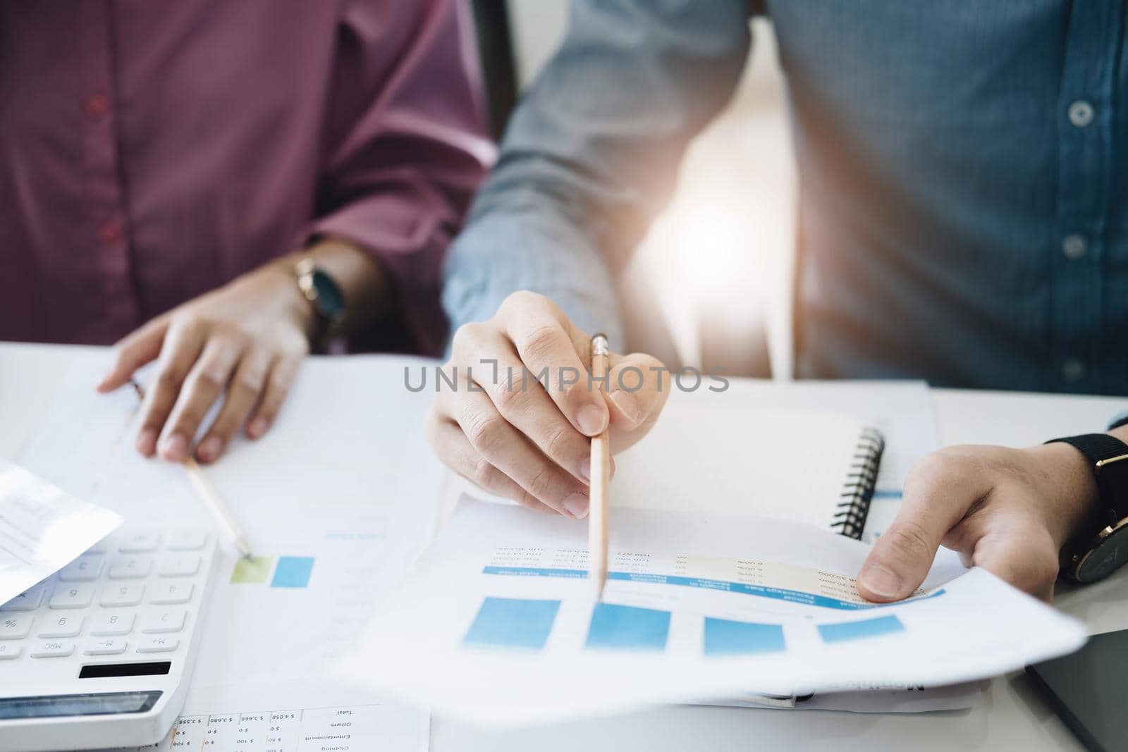 negotiation, analysis, discussion,asian male economist pointing out a document explaining the investment finance program to the company owner to plan marketing and hedging business risks. by Manastrong