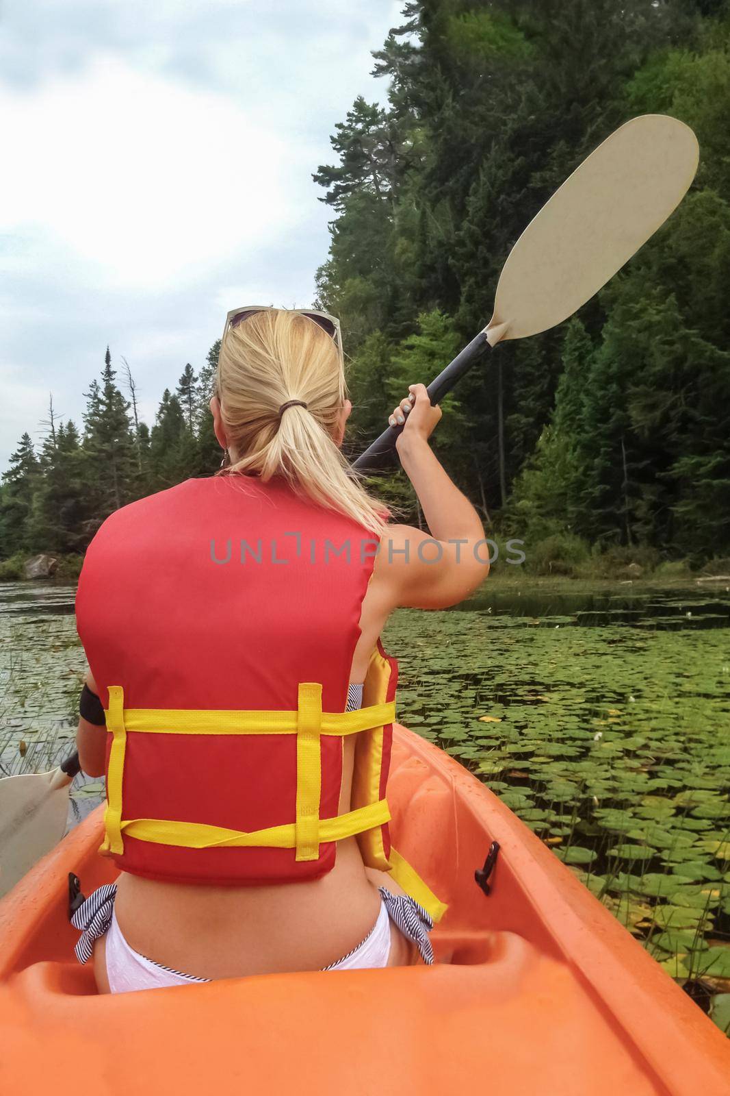 Woman kayaking on the lake with water lilies