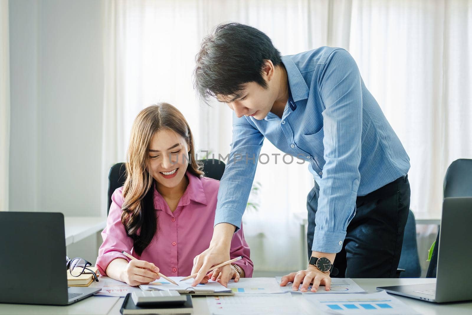 negotiation, analysis, discussion,asian male economist pointing out a document explaining the investment finance program to the company owner to plan marketing and hedging business risks. by Manastrong