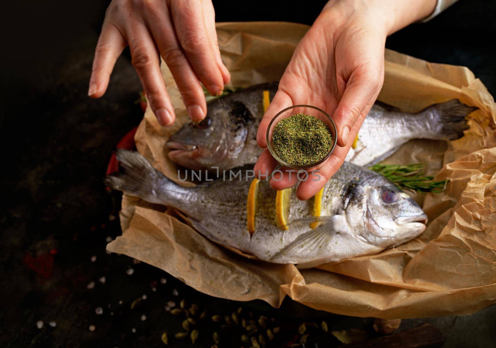 cooking sea fish. Fresh ready to cook raw bream fish dorado with ingredients and seasonings like rosemary, salt, pepper, lime and olive oil, top view by aprilphoto