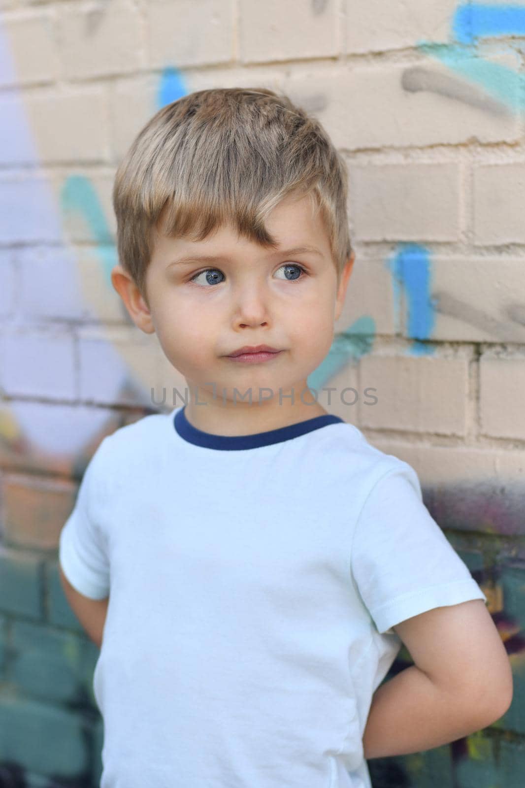 Boy with blue eyes near a colorful wall