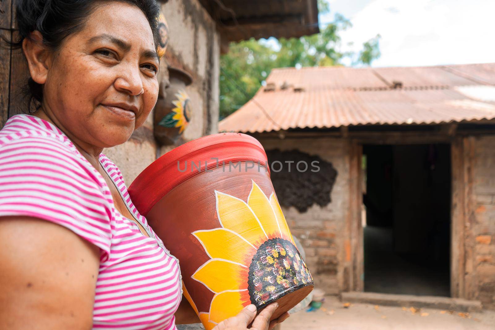 Artisan of La Paz Centro Nicaragua smiling at the camera and holding a clay vase made by herself